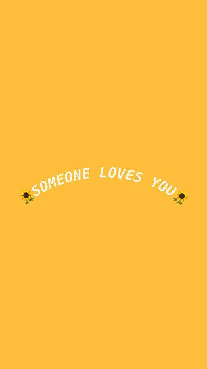 Cute Yellow Aesthetic 桌布 壁紙 — 明亮的黃色背景上，兩個向日葵表情符號之間以白色文字拱形顯示「有人愛你」這句話。