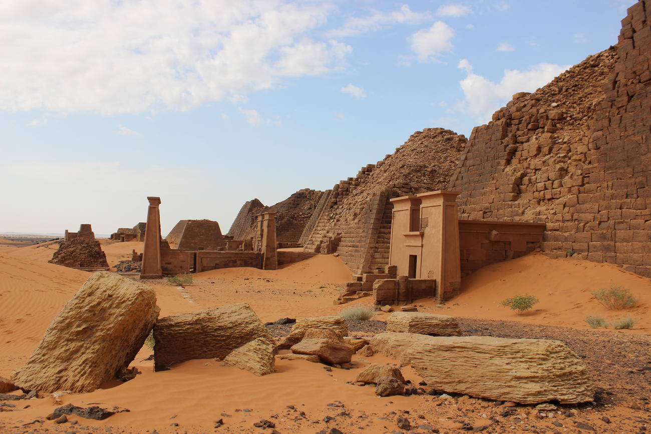 Sudan 桌布 壁紙 — 明亮藍天下，沙漠神廟的古老石頭廢墟，有斷裂的柱子和沙丘。