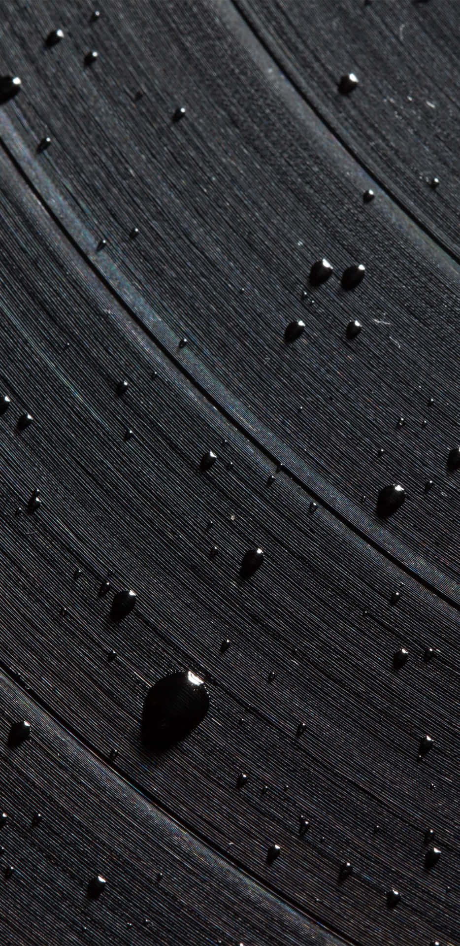 深色木質表面上的雨滴，帶有可見的木紋紋理。 — Google pixel 壁紙