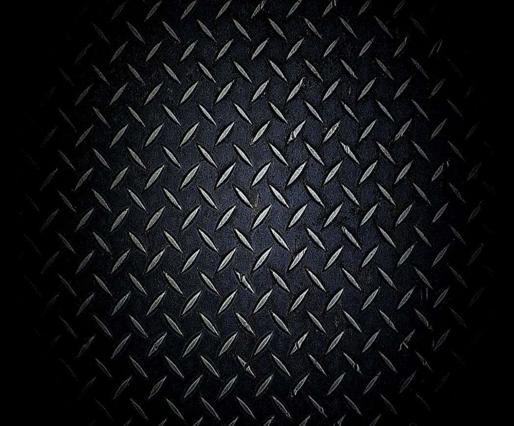 Diamond Plate 桌布 壁紙 — 昏暗燈光下，深色紋理菱形金屬板帶有鋒利脊線和細微刮痕的特寫。