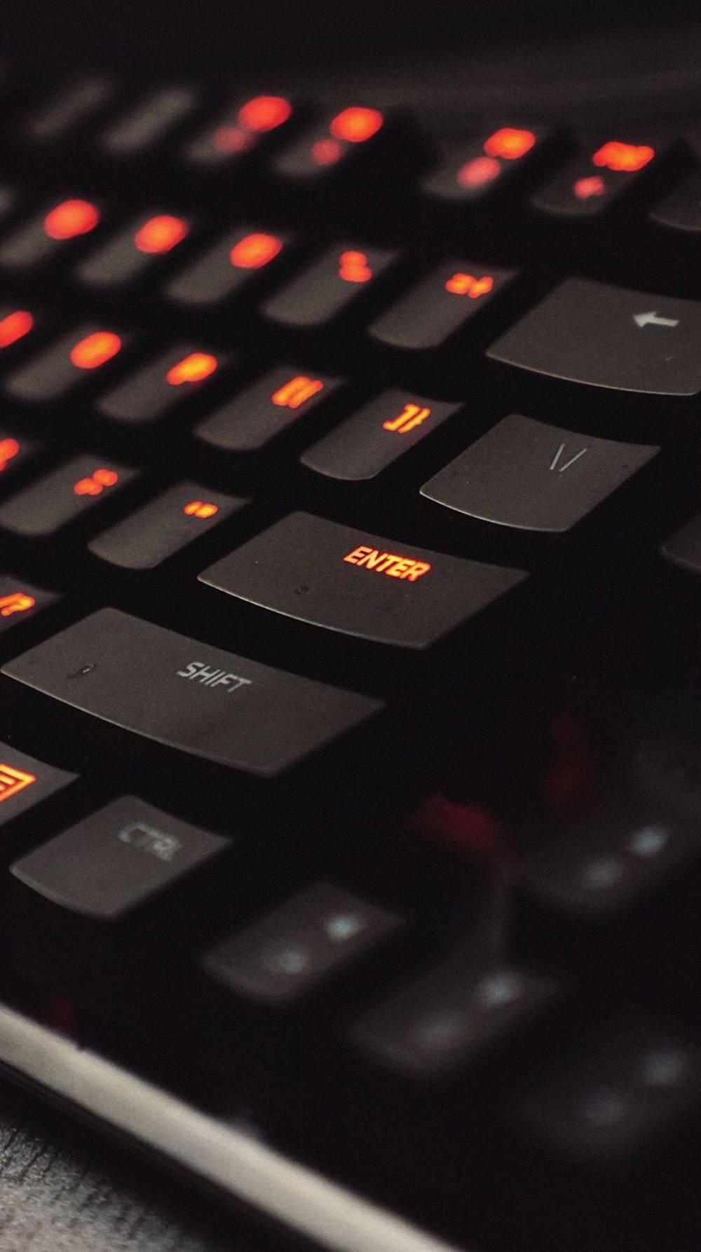 Keyboard Aesthetic 桌布 壁紙 — 昏暗燈光下黑色電競鍵盤的特寫，帶有發光的紅色背光按鍵。