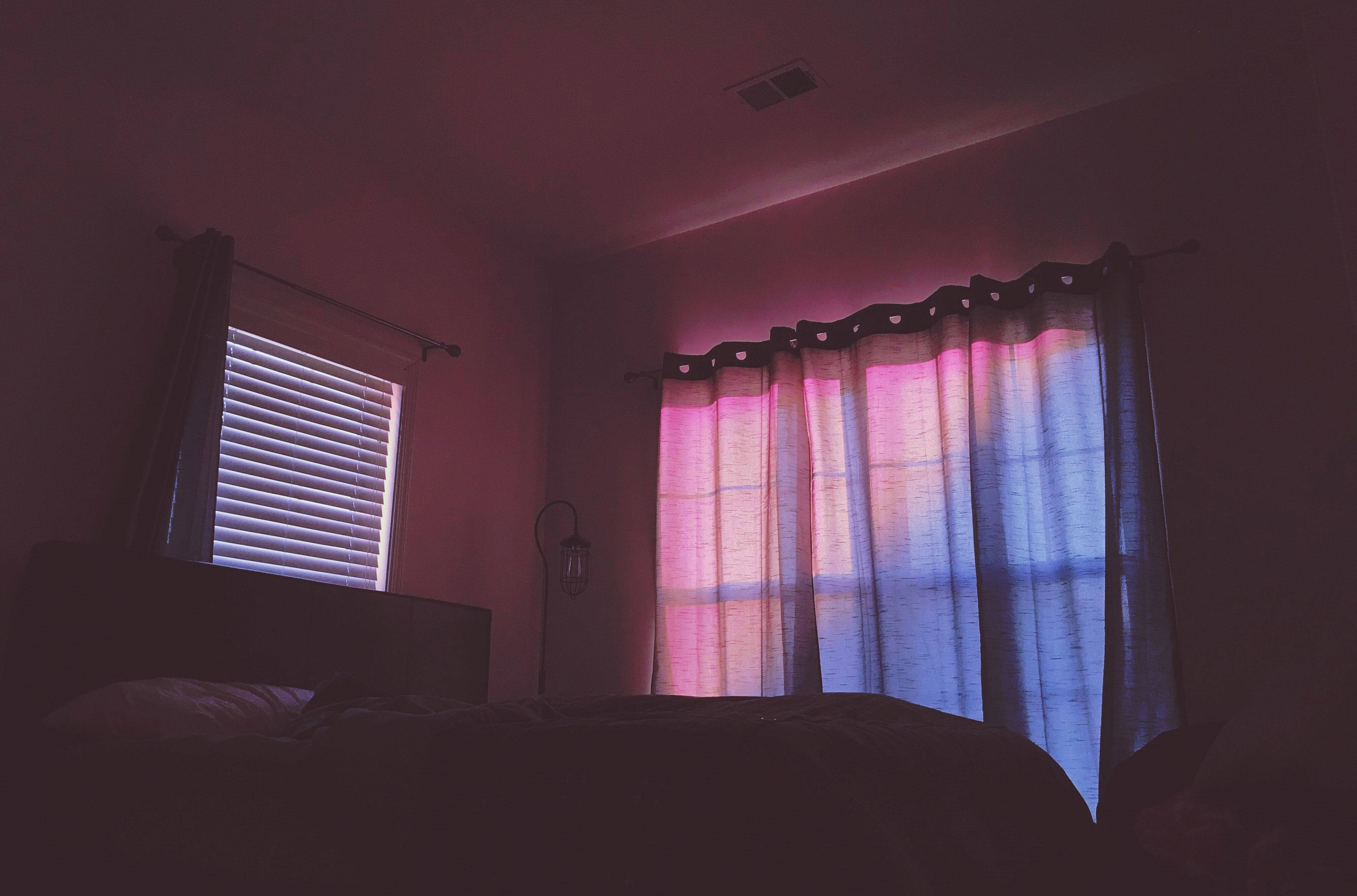 Aesthetic Bedroom 桌布 壁紙 — 昏暗的臥室沐浴在透過薄紗窗簾和百葉窗過濾的柔和粉紅色和藍色光線中。