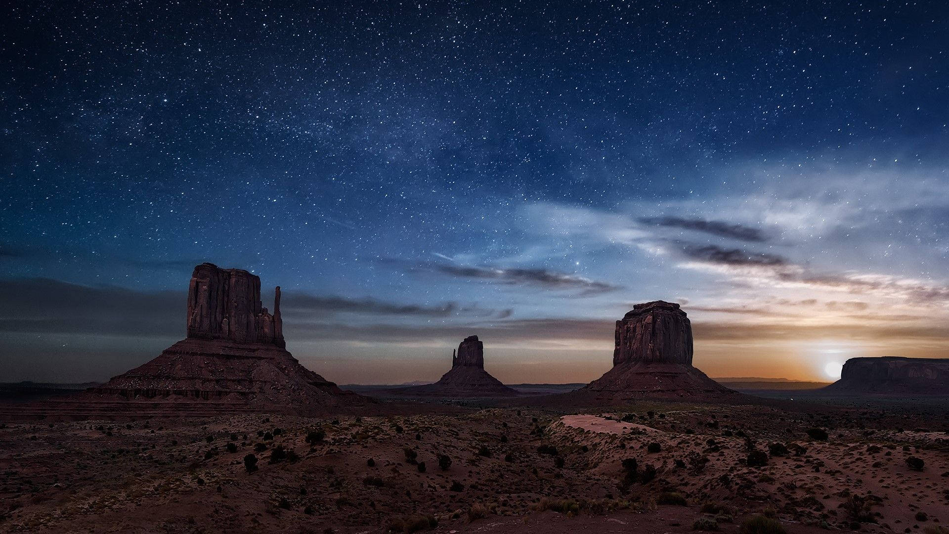 Arizona 桌布 壁紙 — 星光照耀的沙漠巨石在廣闊的夜空下升起，夜空佈滿暮雲和發光的月光。
