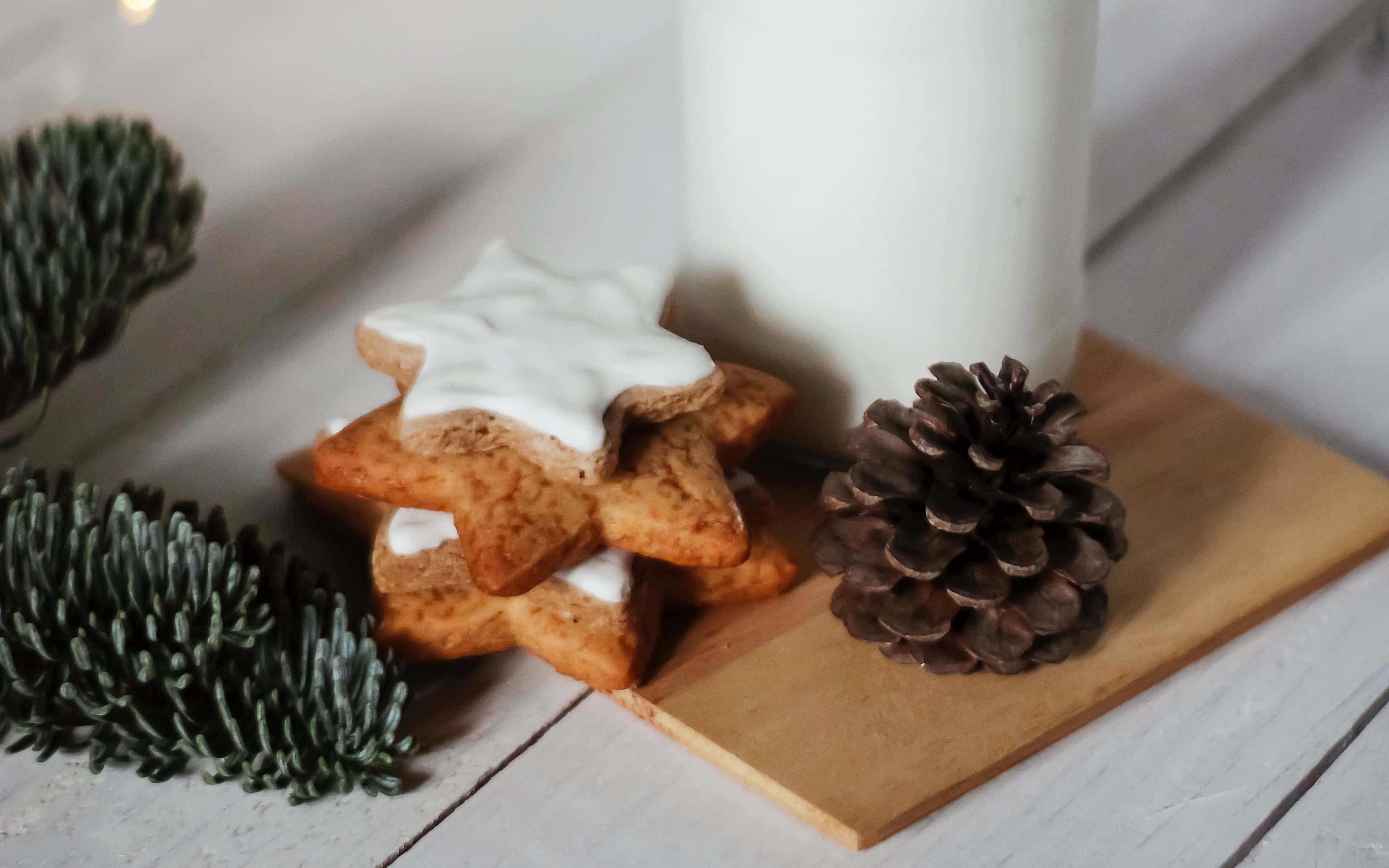 Cookies 桌布 壁紙 — 星形薑餅餅乾搭配白色糖霜，堆疊在松果和冷杉枝旁邊的木板上。