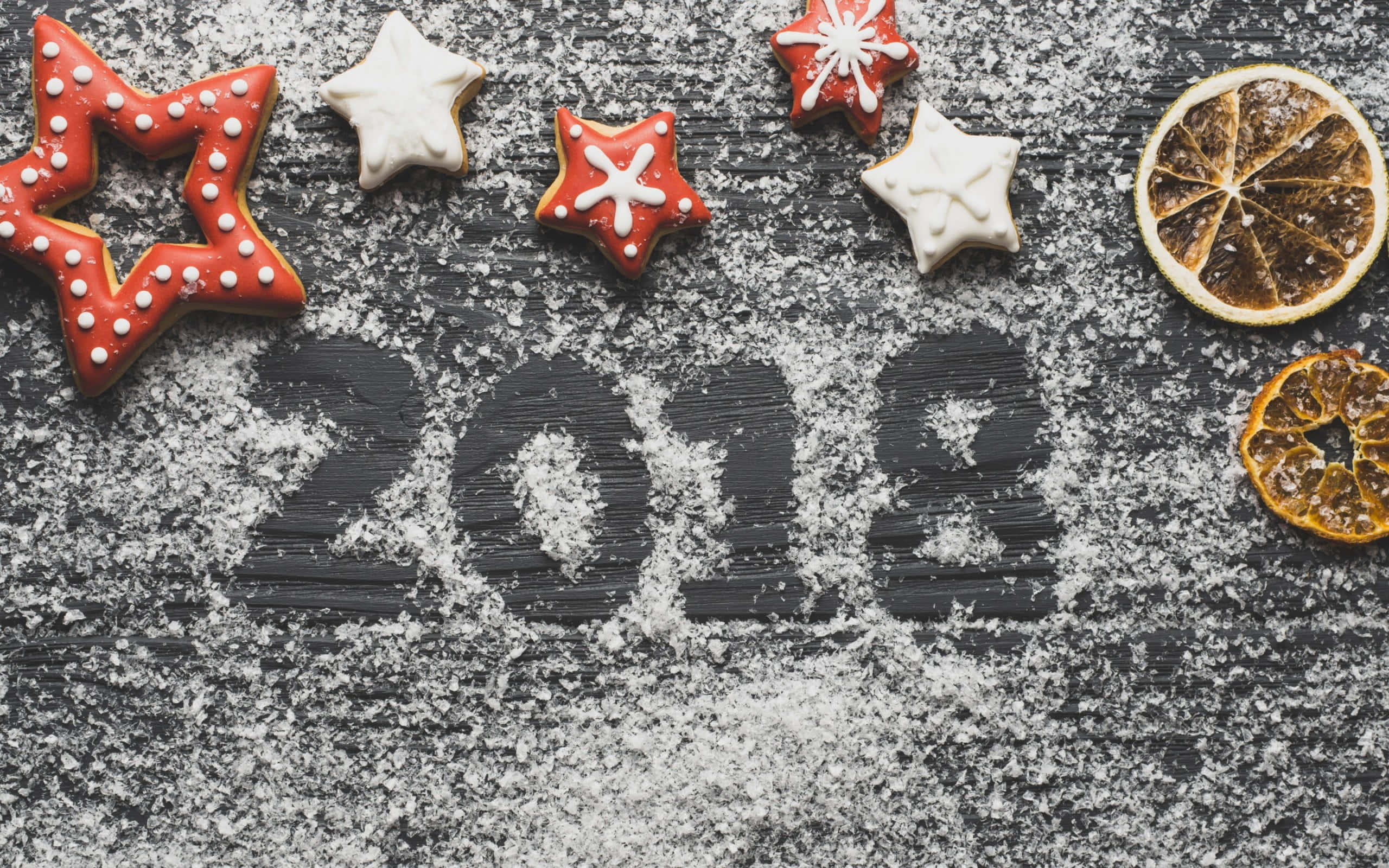 2018 桌布 壁紙 — 星形餅乾和乾橙片圍繞著用糖粉寫在深色紋理表面上的2018年。