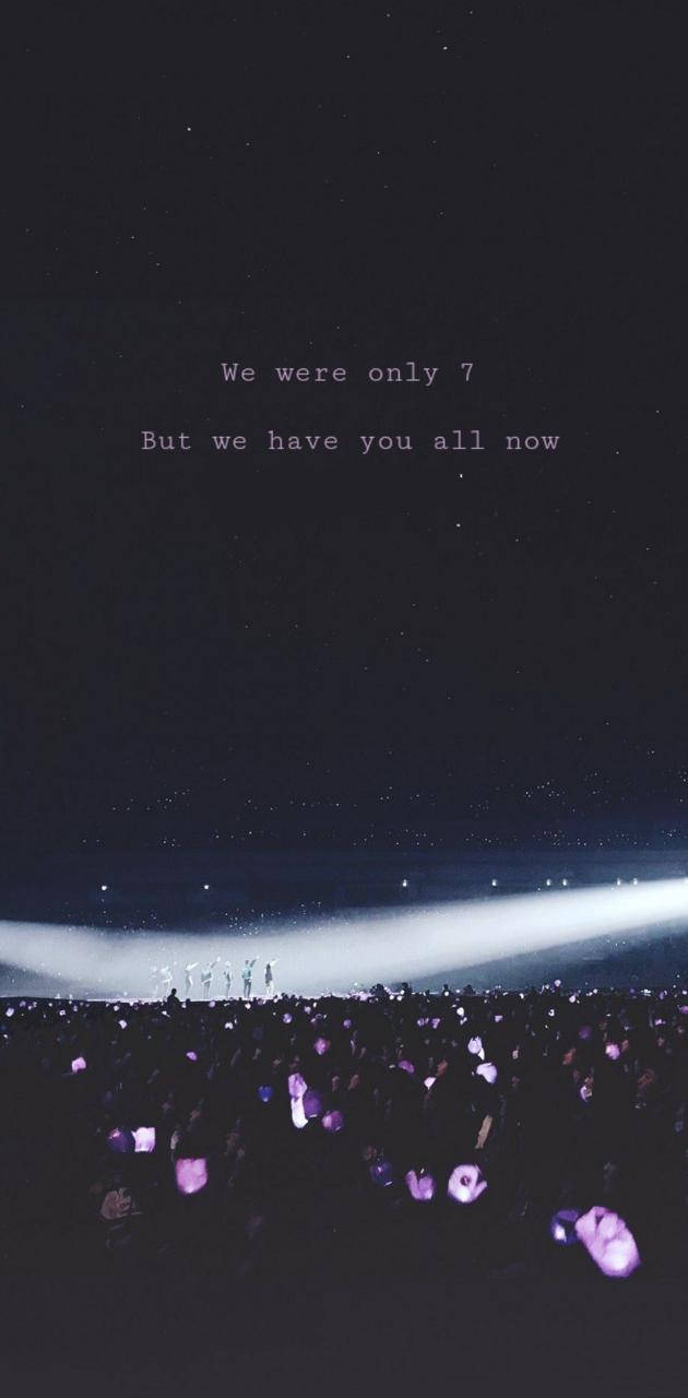 夜間音樂會的人群在舞台燈光下舉著發光的手機，背景是星空。 — BTS ARMY GIF 壁紙