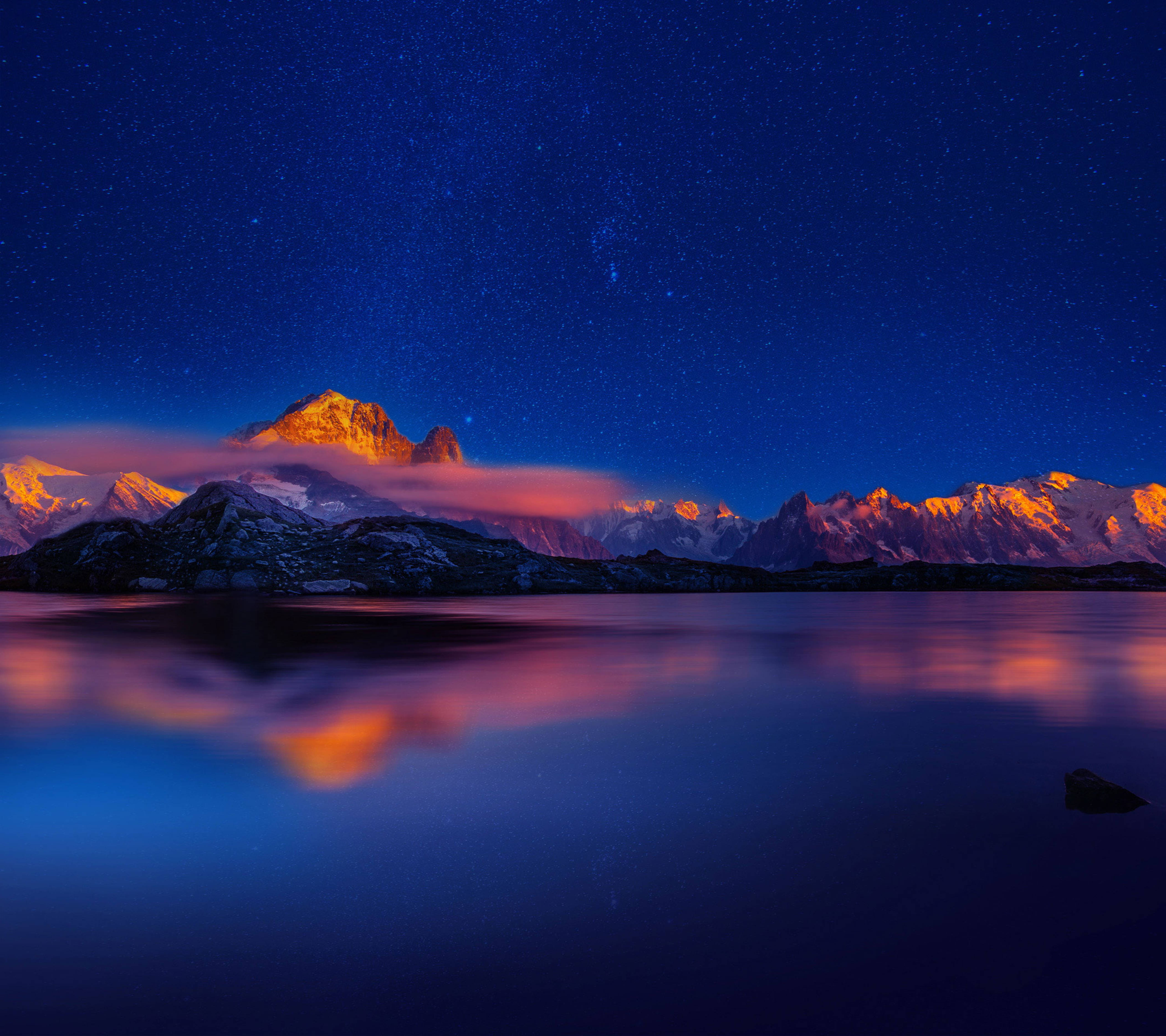 華為 桌布 壁紙 — 星空之夜在積雪的山峰上閃耀，倒映在平靜的湖面上，伴隨著橙色的雲彩。