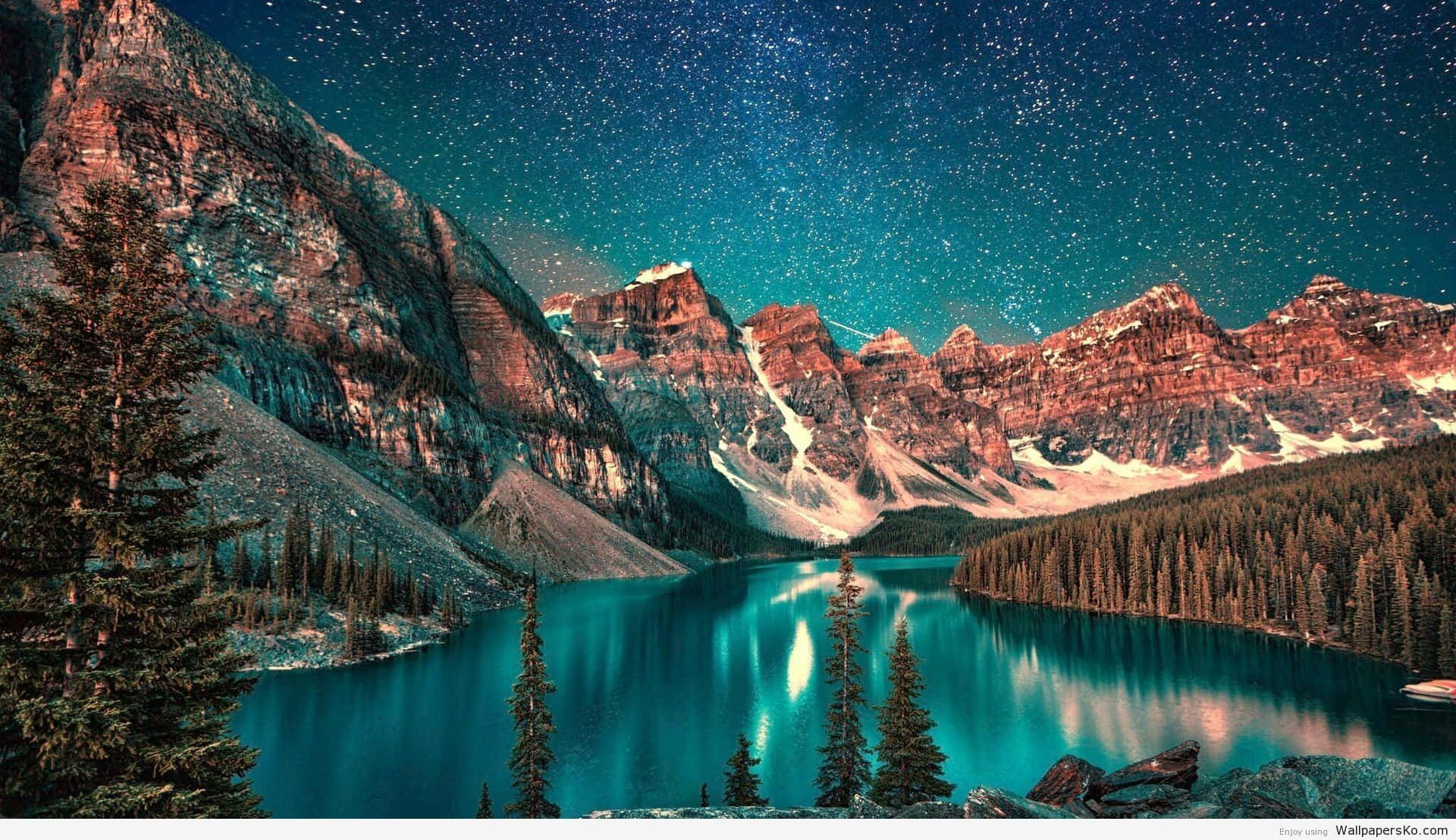 桌布 壁紙 — 星空倒映在一個碧綠色的高山湖泊中，周圍是白雪覆蓋的山峰和常青樹。