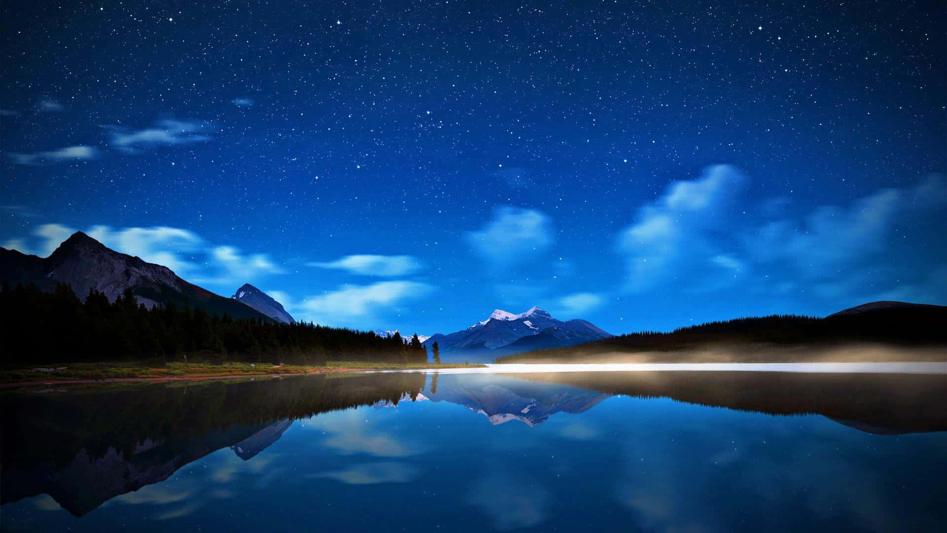 夜晚 桌布 壁紙 — 星空在平靜的湖面上完美倒映，周圍環繞著黑暗的山脈和樹木。