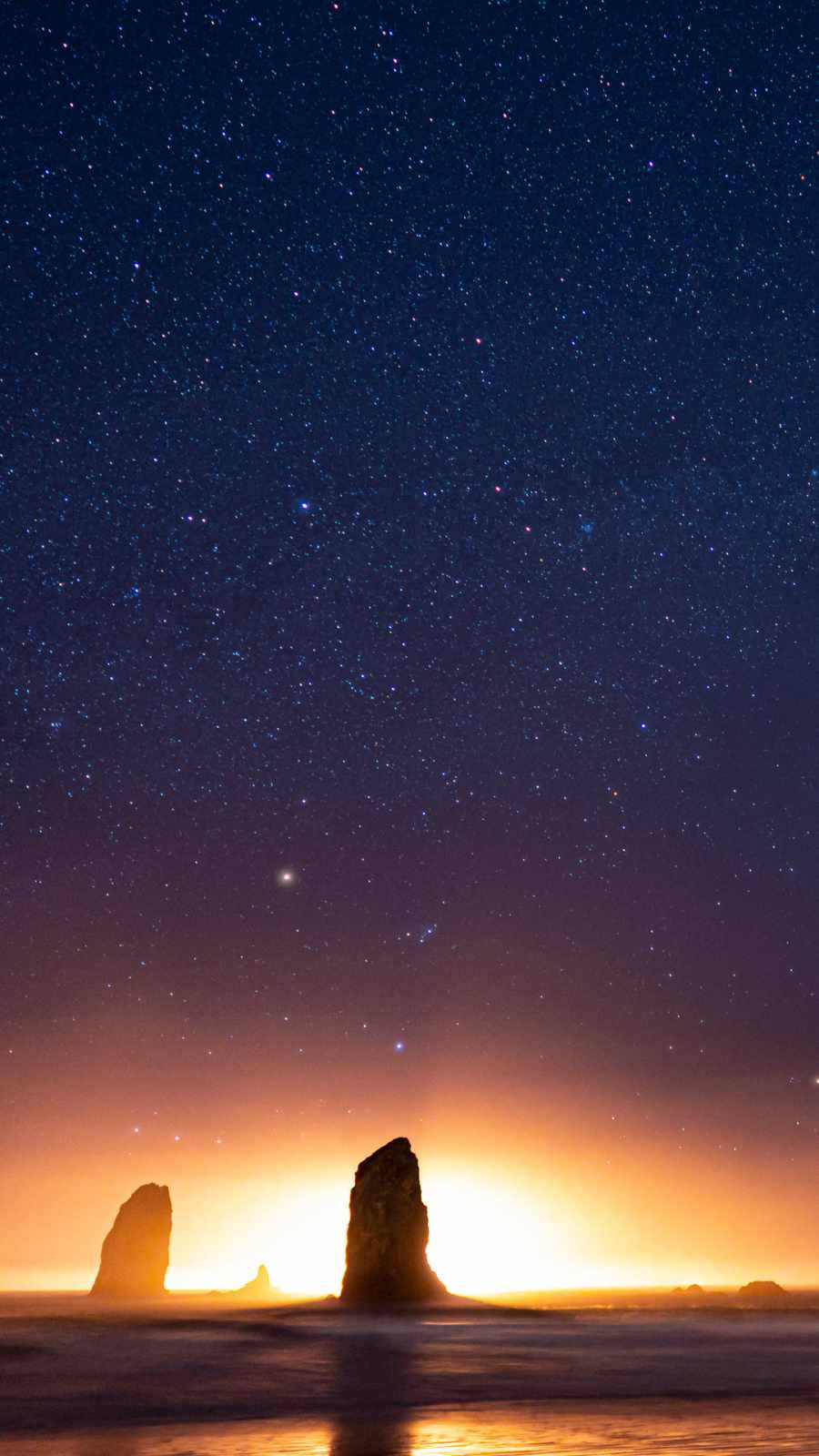 高清 桌布 壁紙 — 星空在黃昏時分在剪影般的海蝕柱上方閃耀，溫暖的地平線光線反射在平靜的水面上。