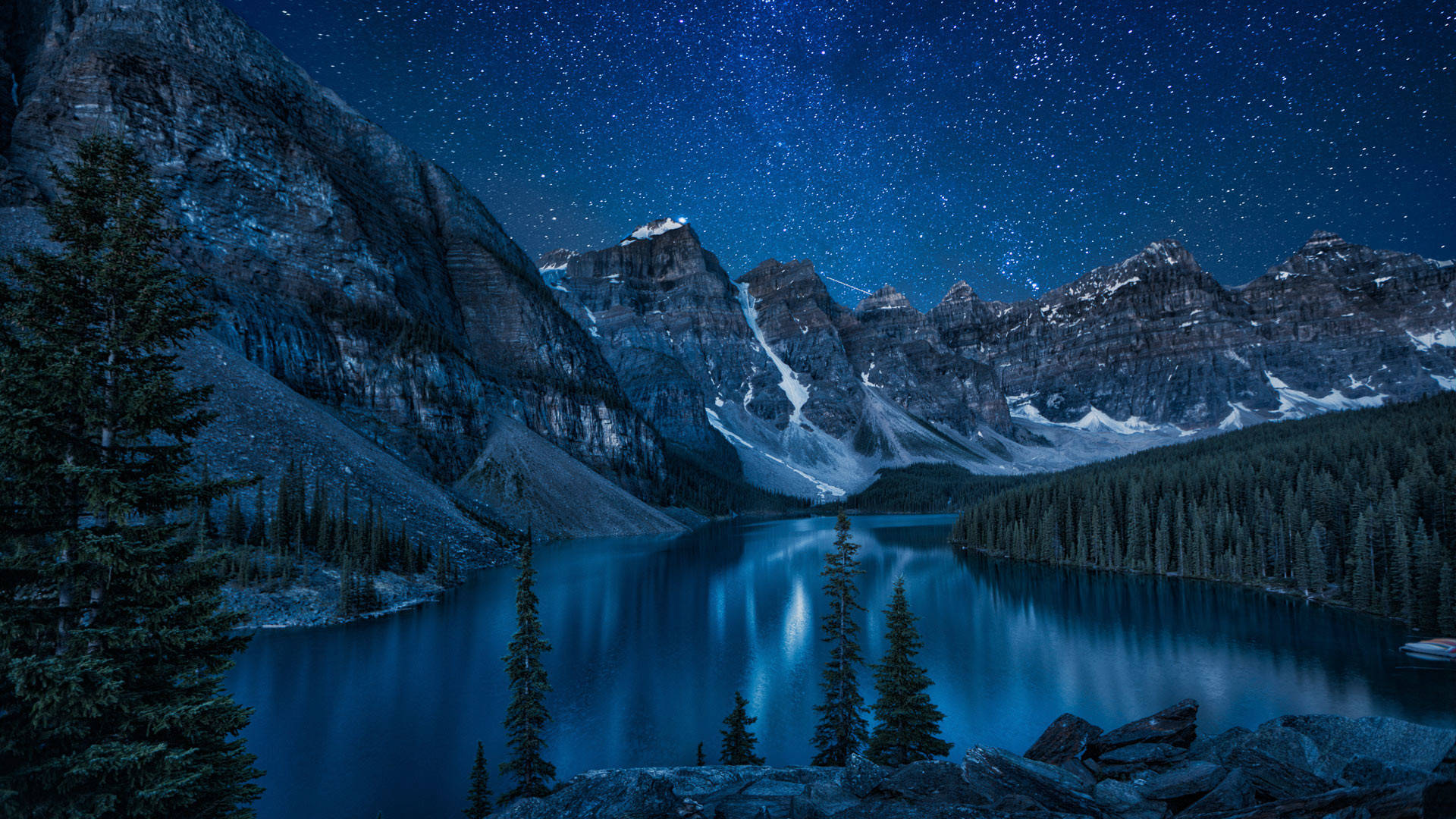 Stars 桌布 壁紙 — 星空夜空倒映在寧靜的山間湖泊中，周圍環繞著積雪的山峰和常青樹。