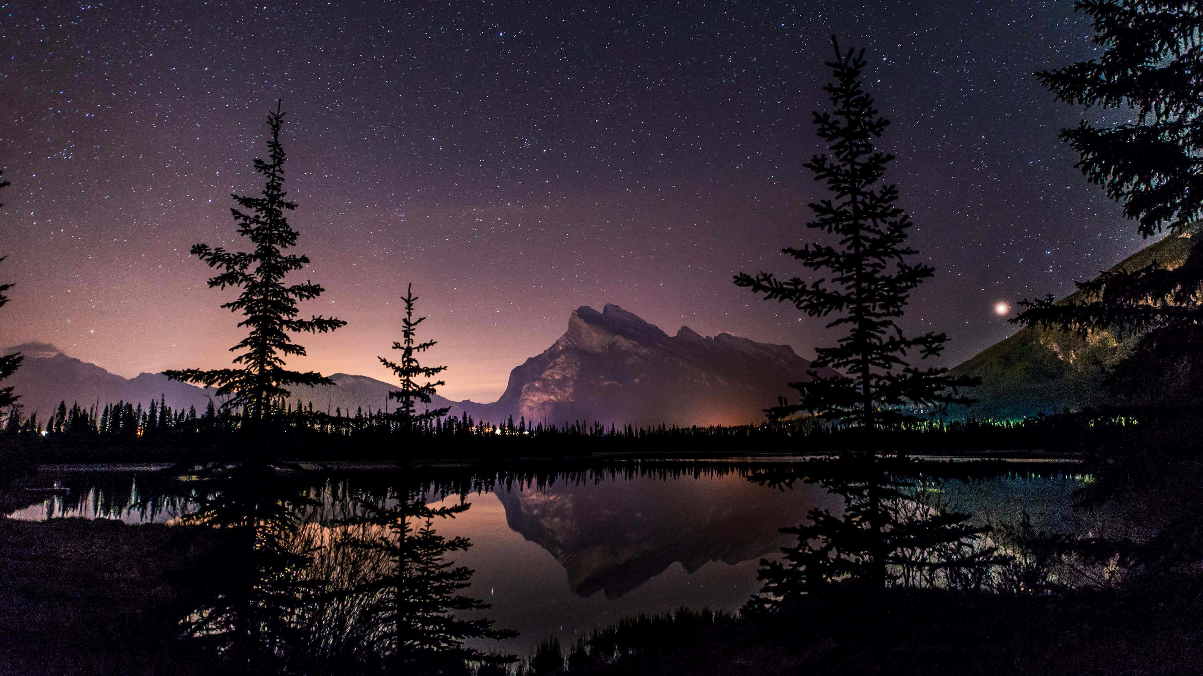 Mountain Aesthetic 桌布 壁紙 — 星空夜空倒映在平靜的湖面上，周圍是松樹的剪影和遠山。