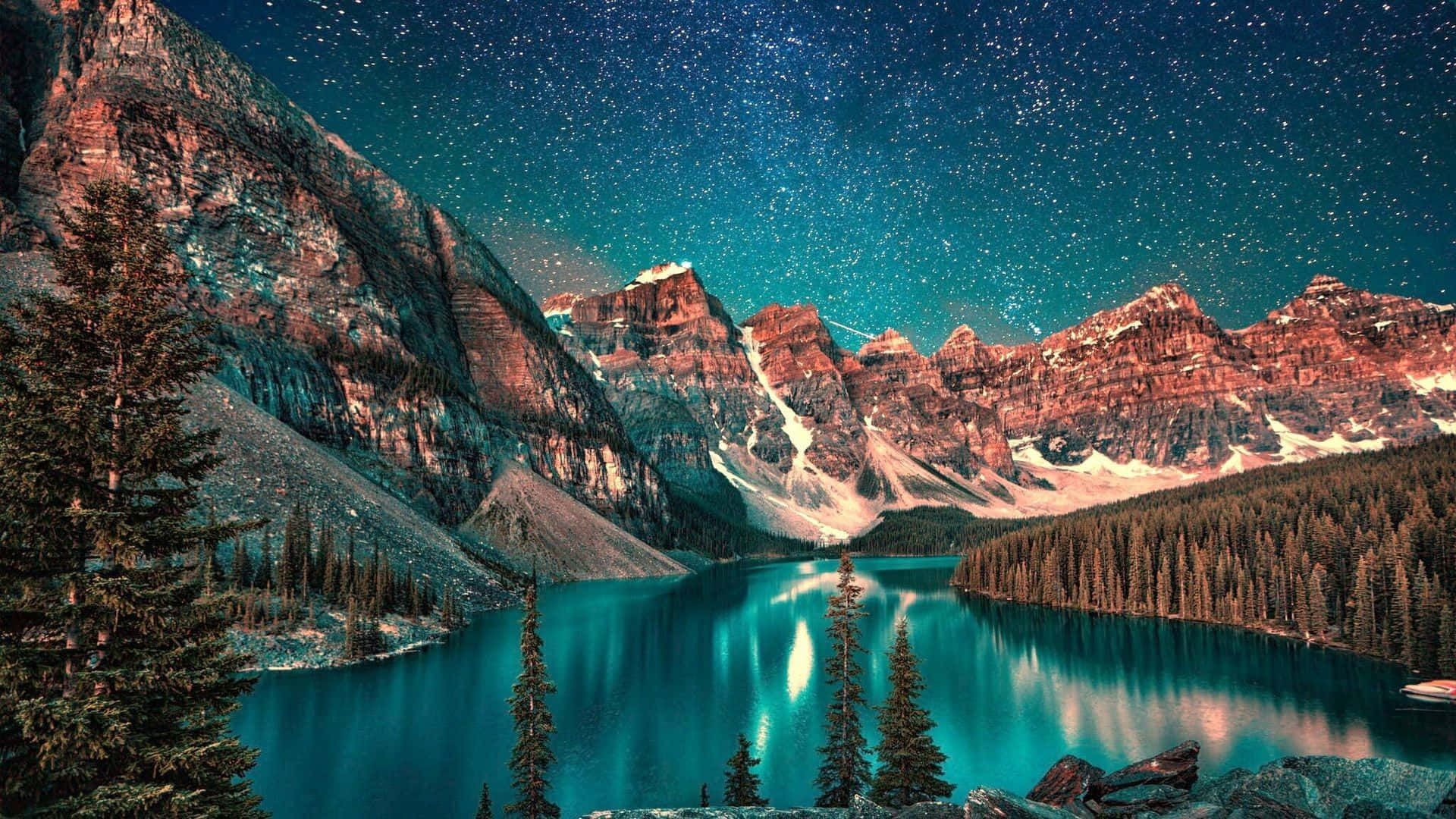 Mac 桌布 壁紙 — 星空夜空倒映在被白雪覆蓋的山脈和常綠樹環繞的綠松石湖中。