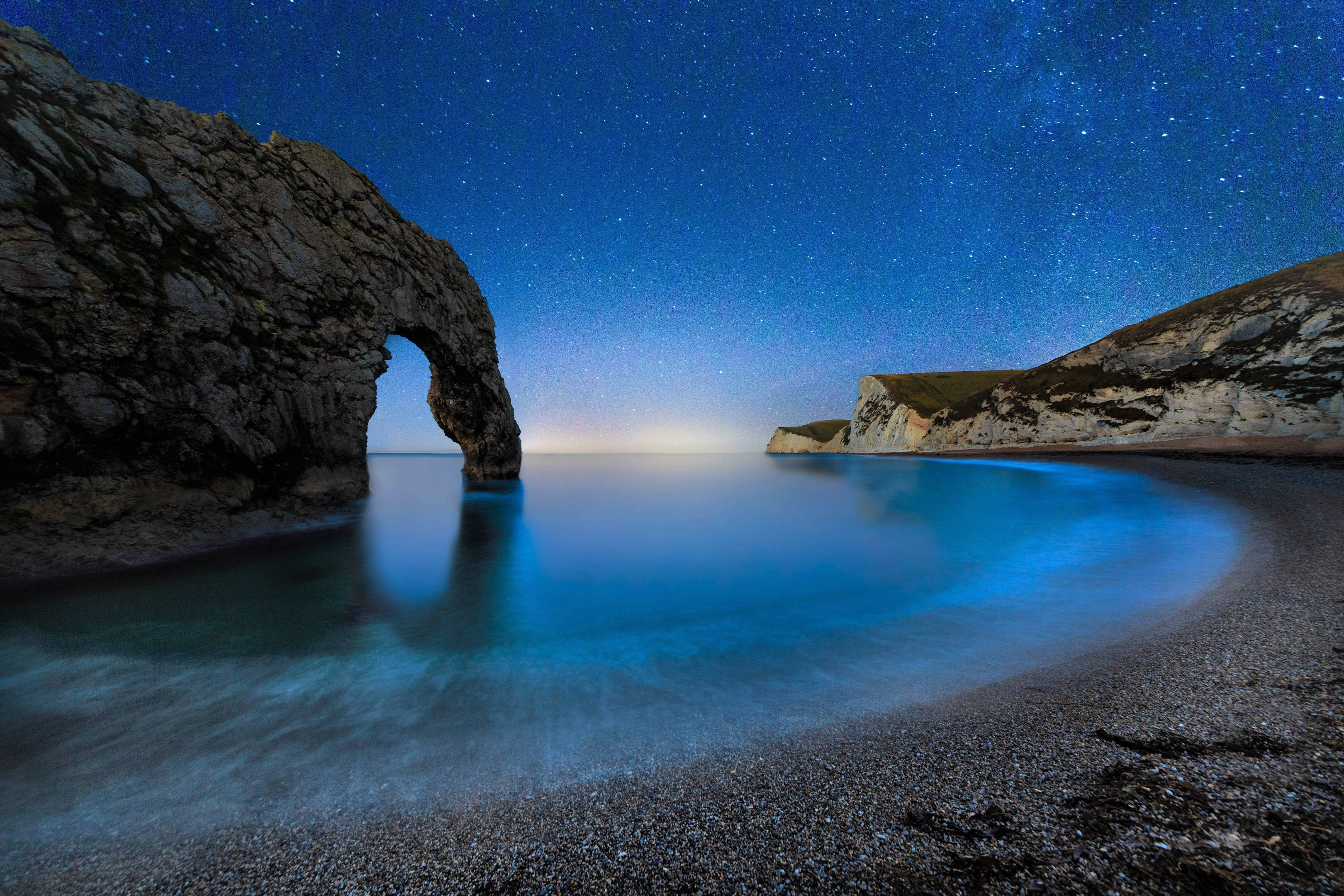 England 桌布 壁紙 — 星空夜空在標誌性的杜德爾門岩層上方拱起，平靜的藍色海水倒映著它的輪廓。