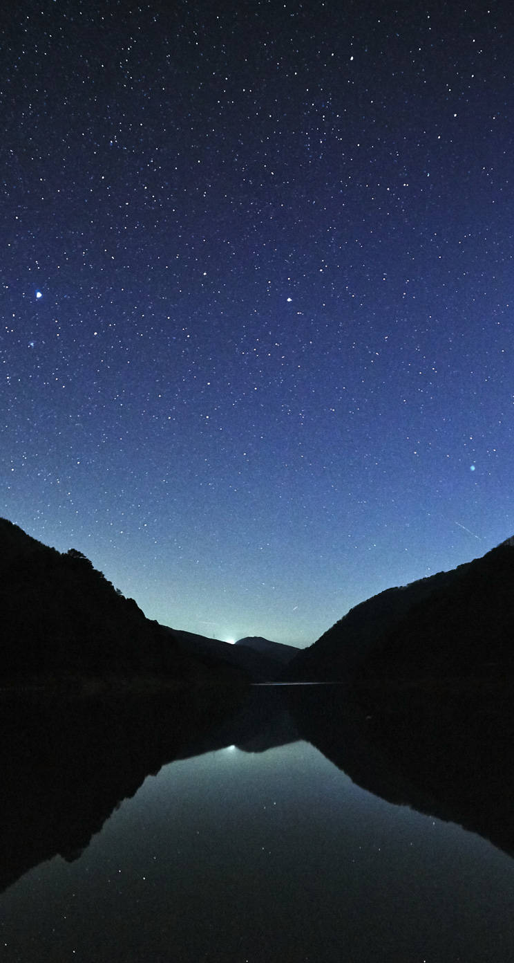 WhatsApp 聊天 桌布 壁紙 — 星空夜空完美倒映在平靜的山湖中，周圍是黑暗的輪廓山丘。