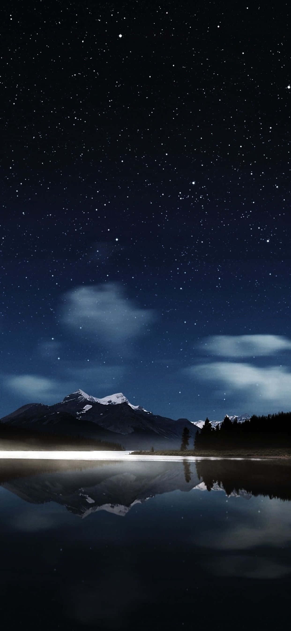 iPhone 桌布 壁紙 — 星空夜空完美地倒映在平靜的湖面上，下方是白雪覆蓋的山脈和剪影般的樹木。