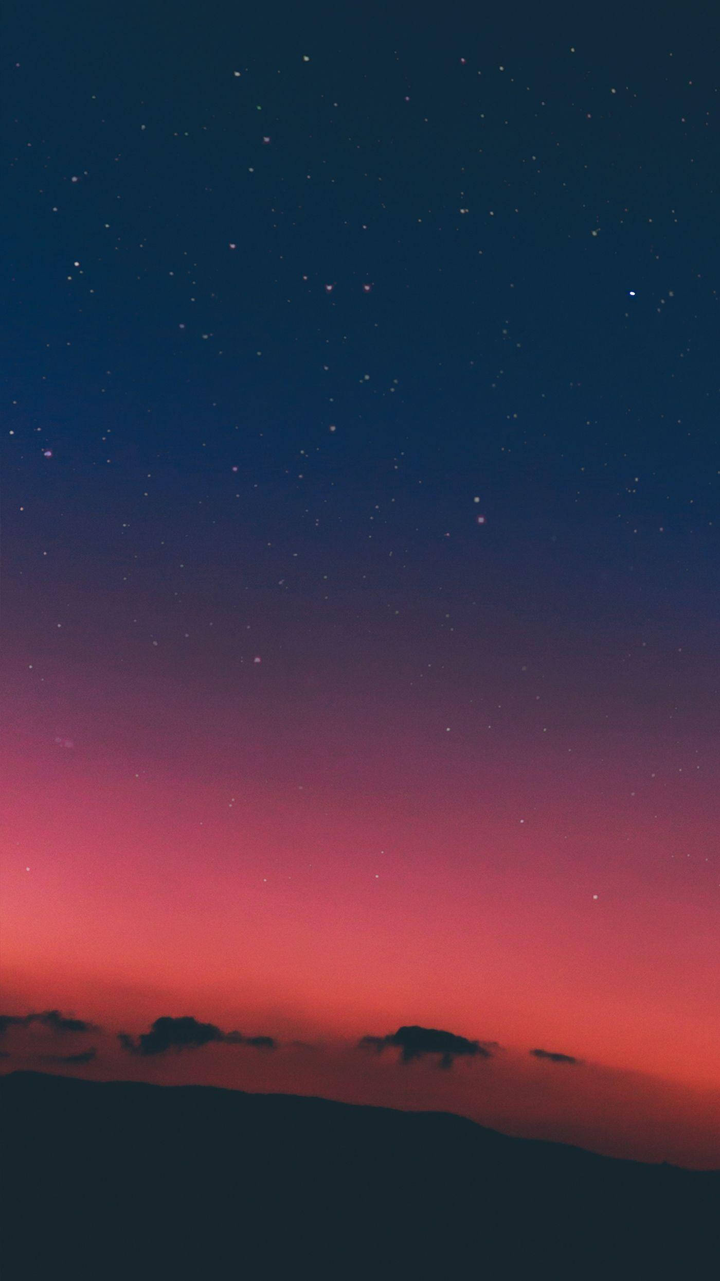 夜空 桌布 壁紙 — 星空暮色天空從深藍色過渡到火熱的粉紅色，位於剪影山脊之上。