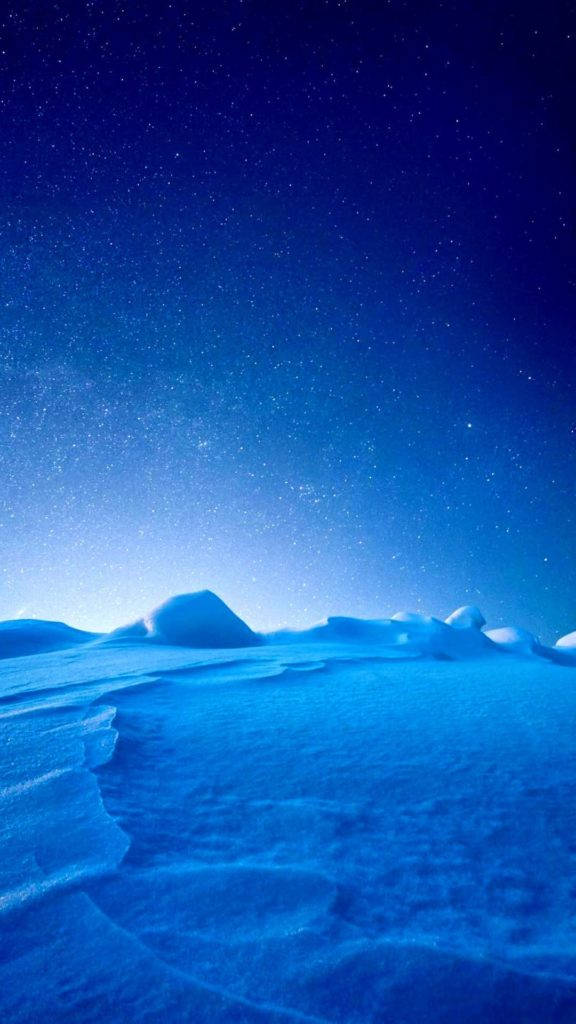 iPhone 動態 桌布 壁紙 — 星空籠罩著寧靜的雪景，帶有柔和的藍色調和溫和起伏的地形。