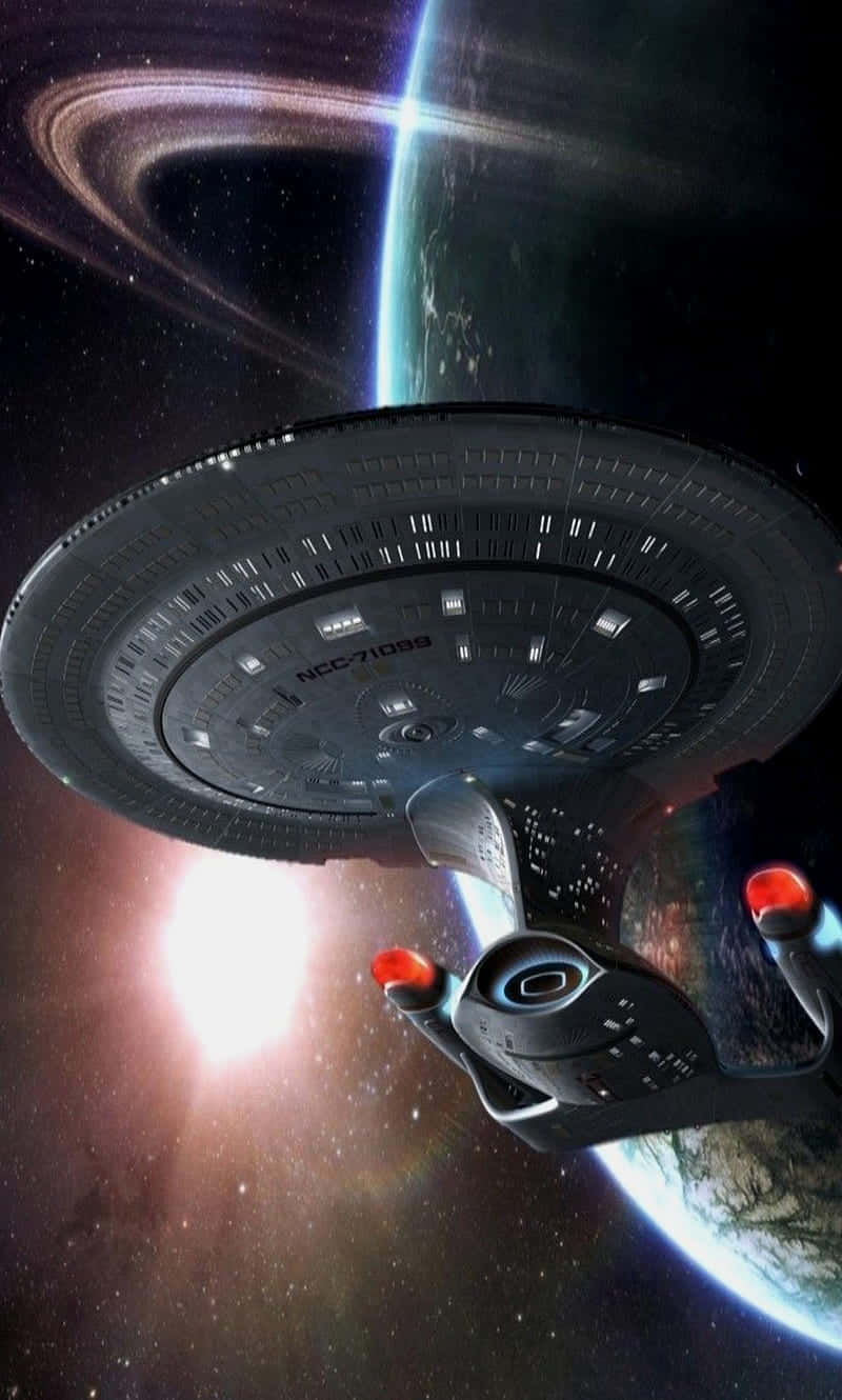 Star Trek Enterprise 桌布 壁紙 — 星艦企業號 NCC-1701 飛過一個帶環行星，背後有發光的星爆在深空中。