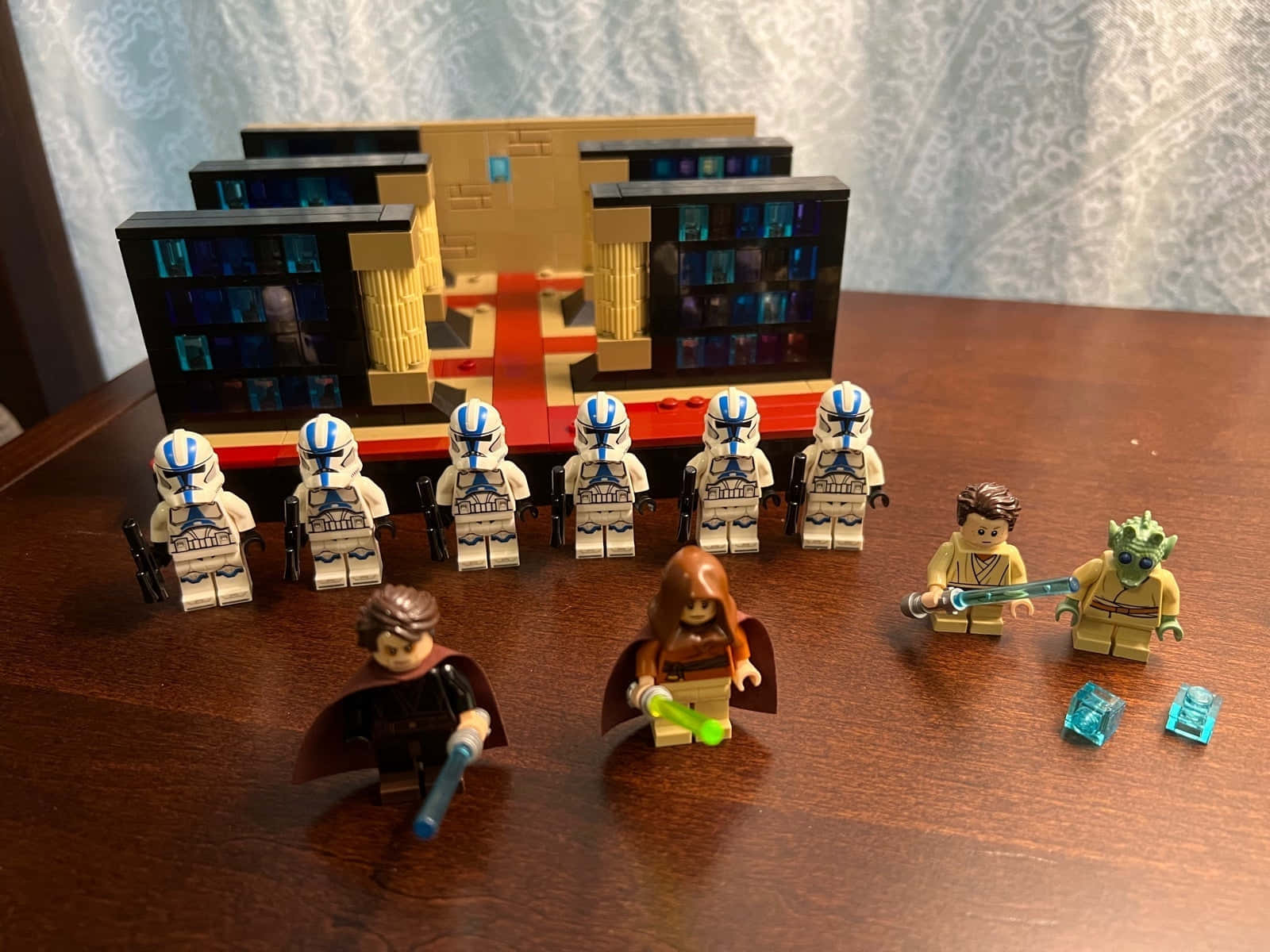 The Order 66 桌布 壁紙 — 星際大戰 LEGO 人偶，包括複製人軍團和絕地武士，擺放在木桌上，前面有一個精細的 LEGO 建築。