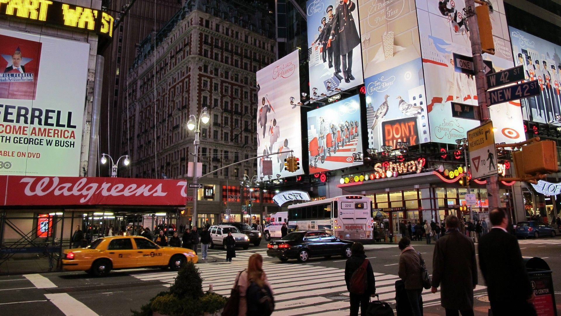 Broadway 桌布 壁紙 — 時代廣場充滿活力的夜景，有發光的廣告牌、黃色的士和穿越繁忙十字路口的行人。