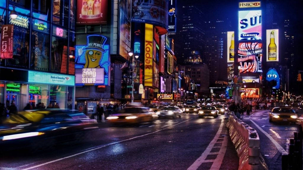 New 桌布 壁紙 — 時代廣場充滿活力的夜景，發光的廣告牌和潮濕街道上流動的車燈。
