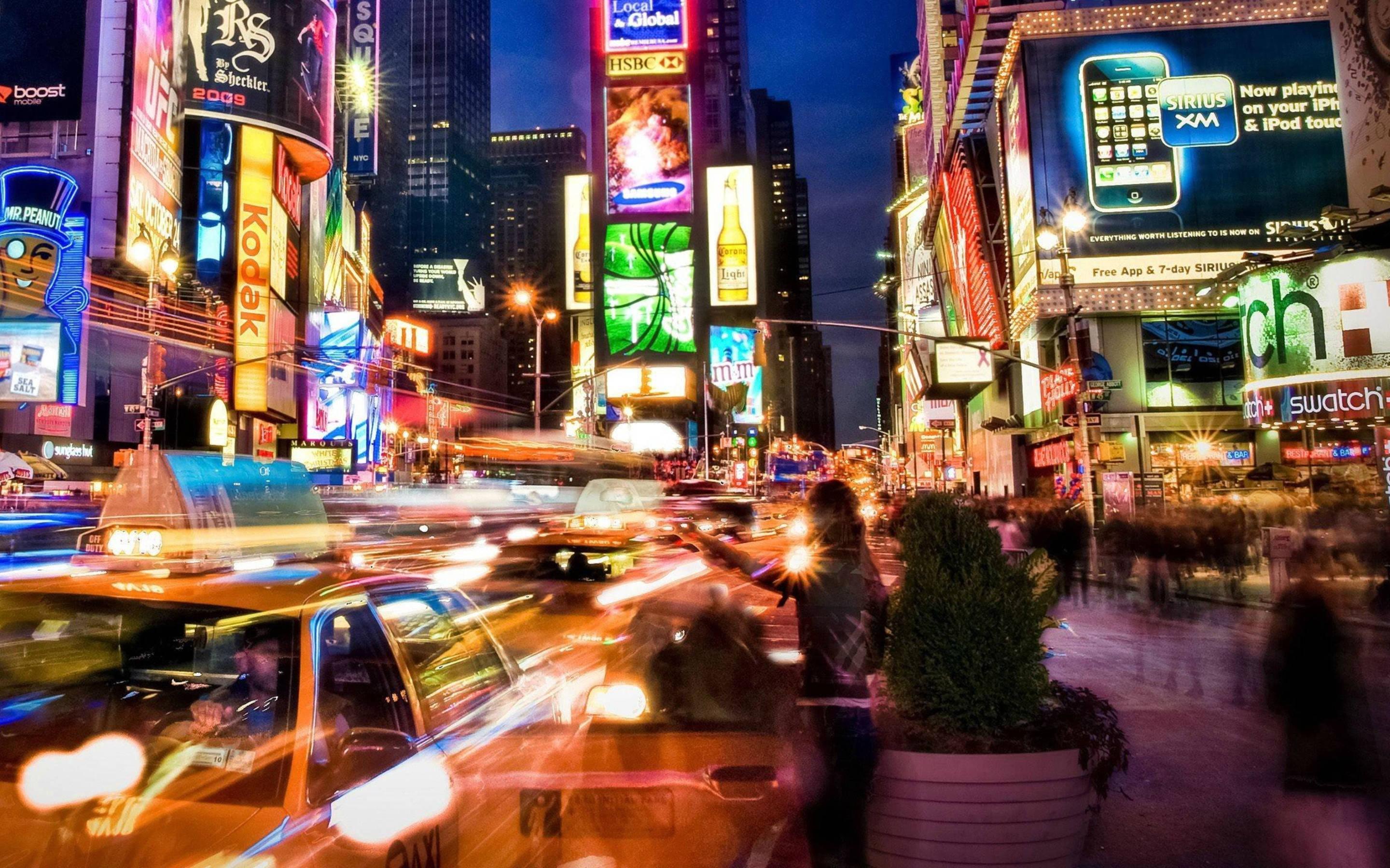 X 桌布 壁紙 — 時代廣場充滿活力的夜景，計程車燈光劃過，閃爍的廣告牌照亮繁忙的街道。
