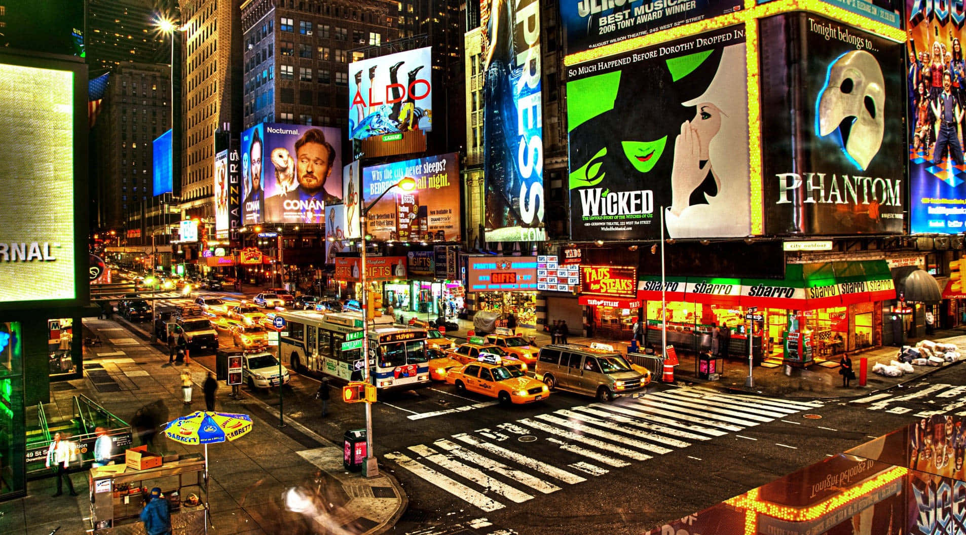 New York 桌布 壁紙 — 時代廣場充滿活力的夜景，閃爍的廣告牌、計程車和繁華的街道反射著霓虹燈光。