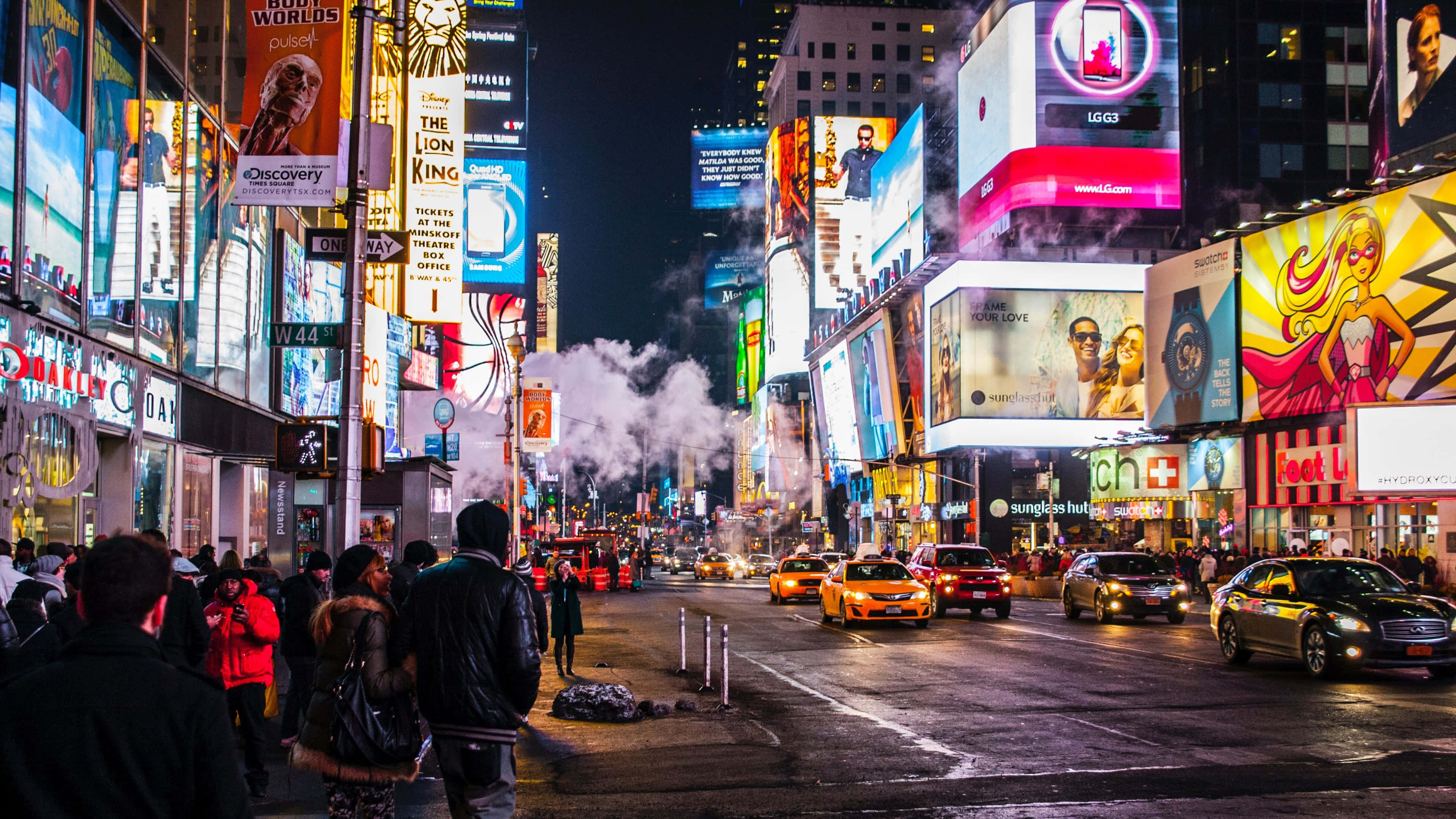 桌布 壁紙 — 時代廣場充滿活力的夜景，閃爍的廣告牌、人行道上升起的蒸汽，以及人群在黃色出租車間行走。