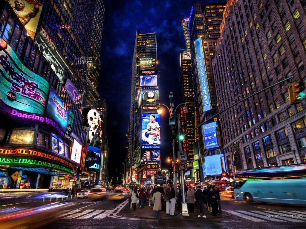 Broadway 桌布 壁紙 — 時代廣場充滿活力的夜景，閃爍的廣告牌和流動的車流在黑暗的天空下。