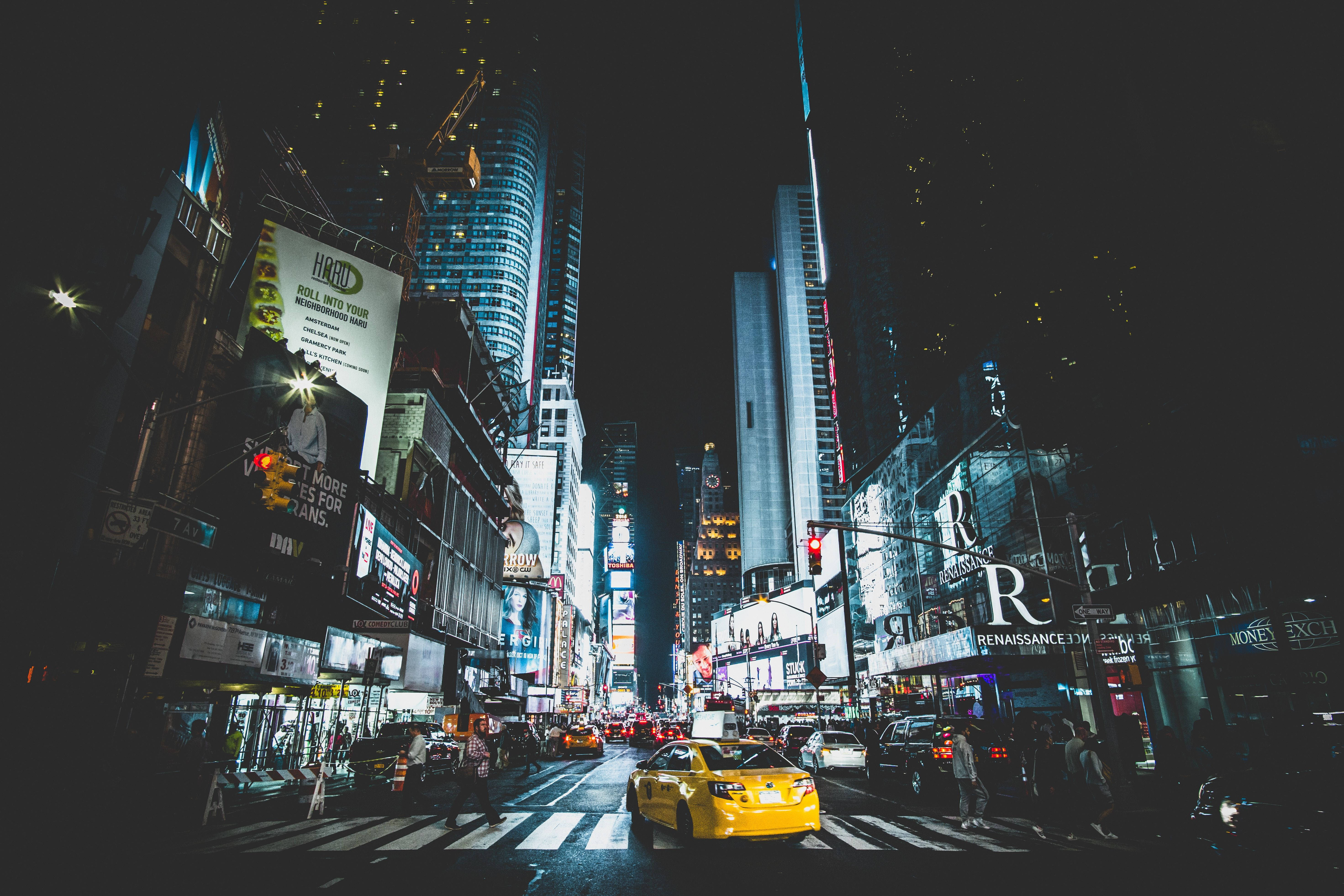 New York 桌布 壁紙 — 時代廣場充滿活力的夜景，高聳的摩天大樓在霓虹燈下閃耀，一輛黃色的計程車穿過繁忙的街道。