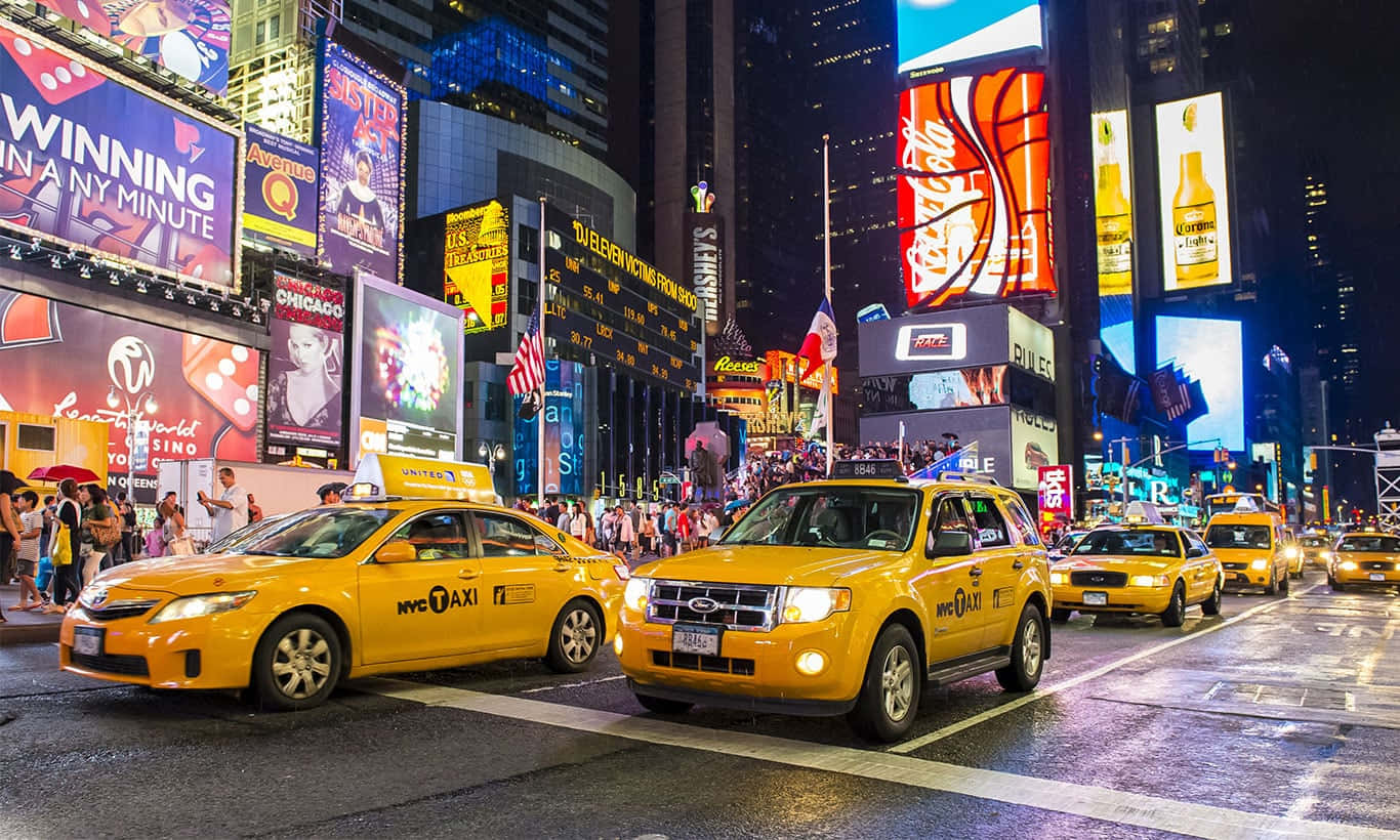 Yellow Cab 桌布 壁紙 — 時代廣場充滿活力的夜景，黃色的士和耀眼的數位廣告看板照亮了繁華的城市街道。