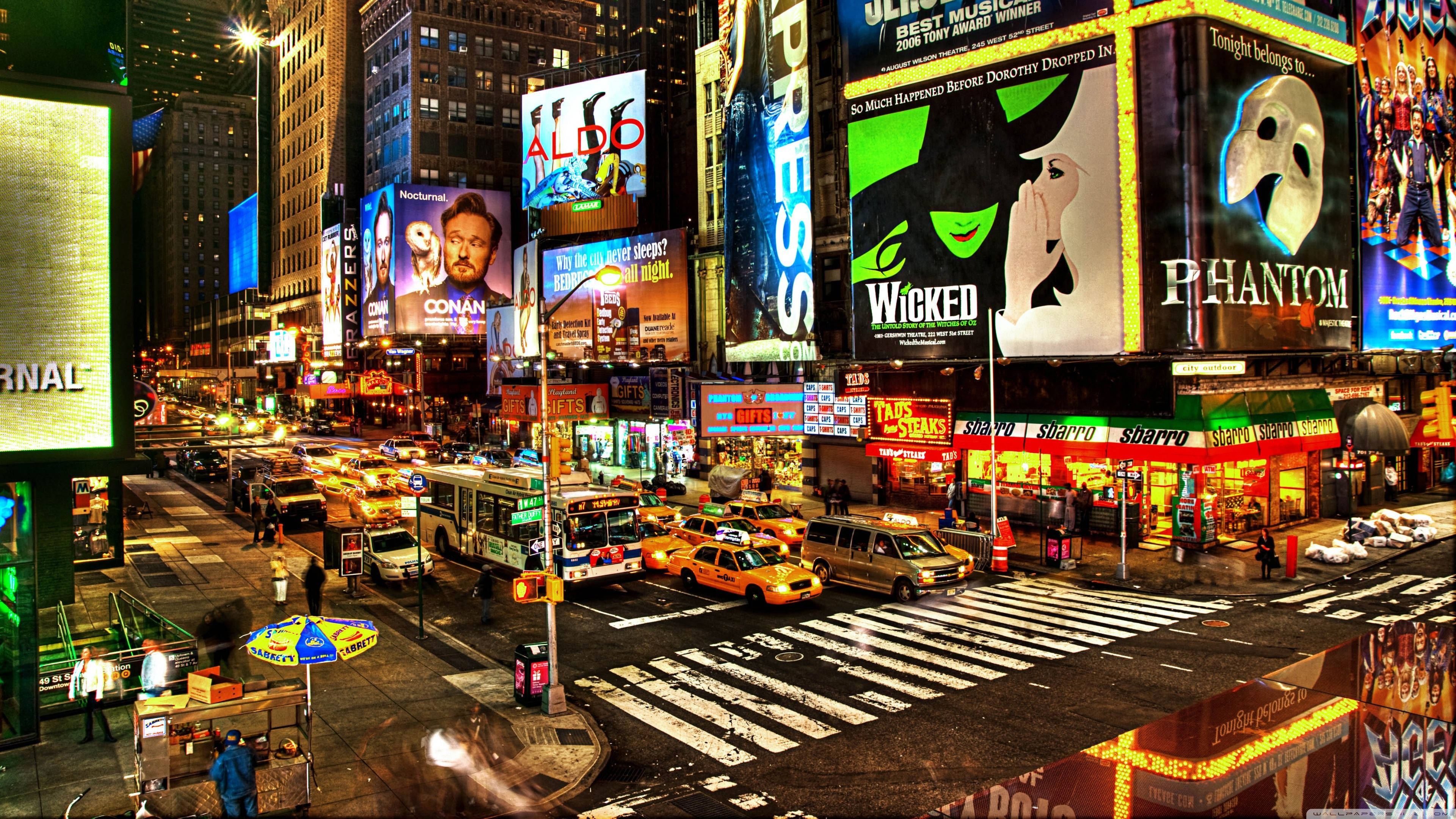 New York Street 桌布 壁紙 — 時代廣場充滿活力的夜間城市景觀，閃爍的廣告牌、計程車和繁華的街道反射著霓虹燈光。