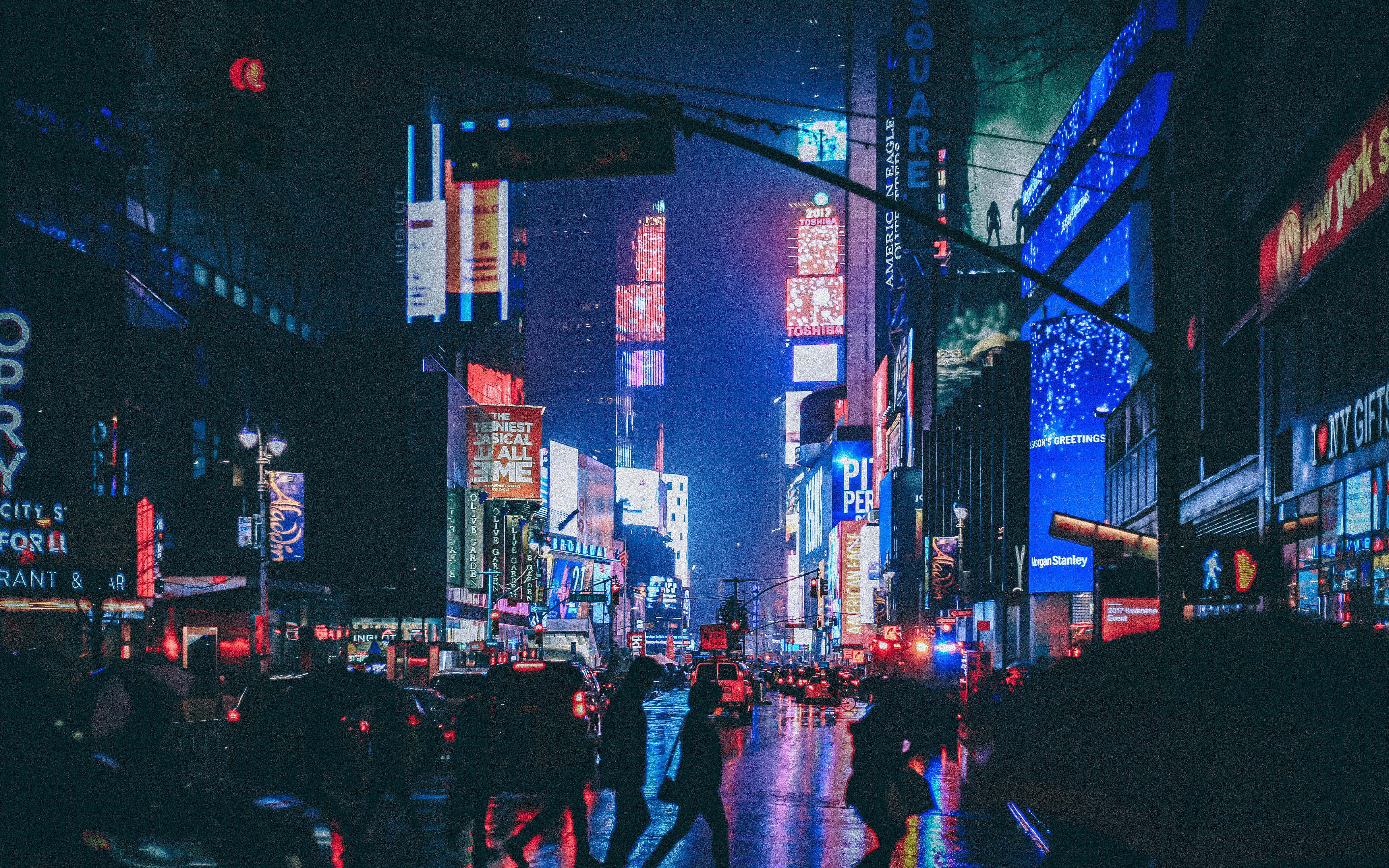 Neon City Aesthetic 桌布 壁紙 — 時代廣場的雨夜，發光的霓虹招牌映照在濕漉漉的人行道上，模糊的行人穿過馬路。