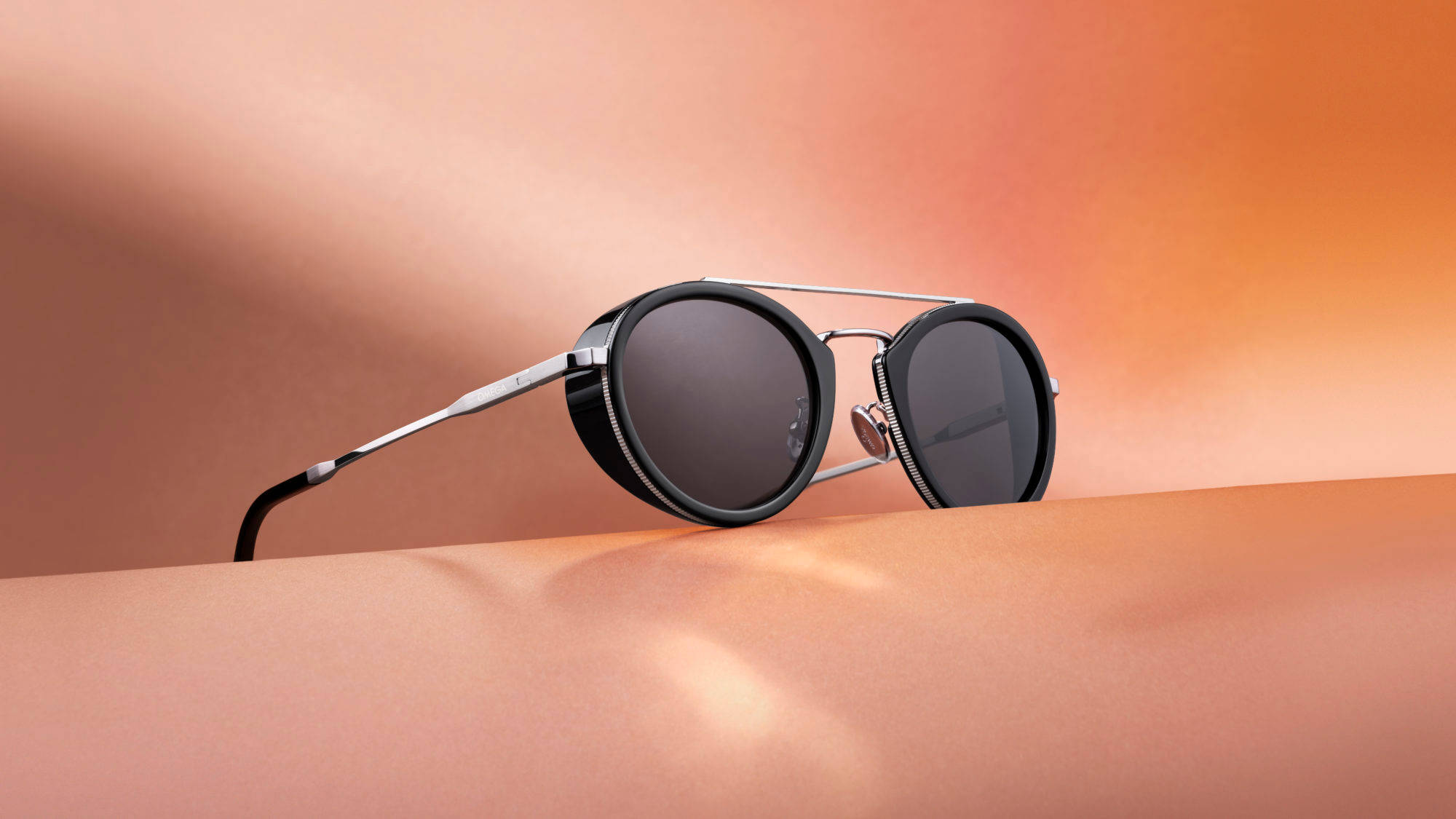 Sunglasses 桌布 壁紙 — 時尚圓形太陽眼鏡配銀色鏡框，在柔和光線下放置於光滑的蜜桃漸變表面上。
