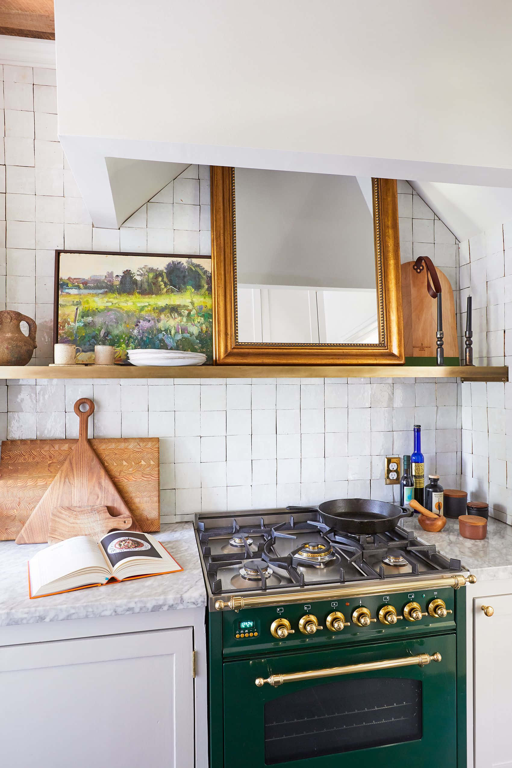 Kitchen Wall 桌布 壁紙 — 時尚廚房，配有綠色爐灶、黃銅旋鈕、白色瓷磚和打開的書放在大理石檯面上。