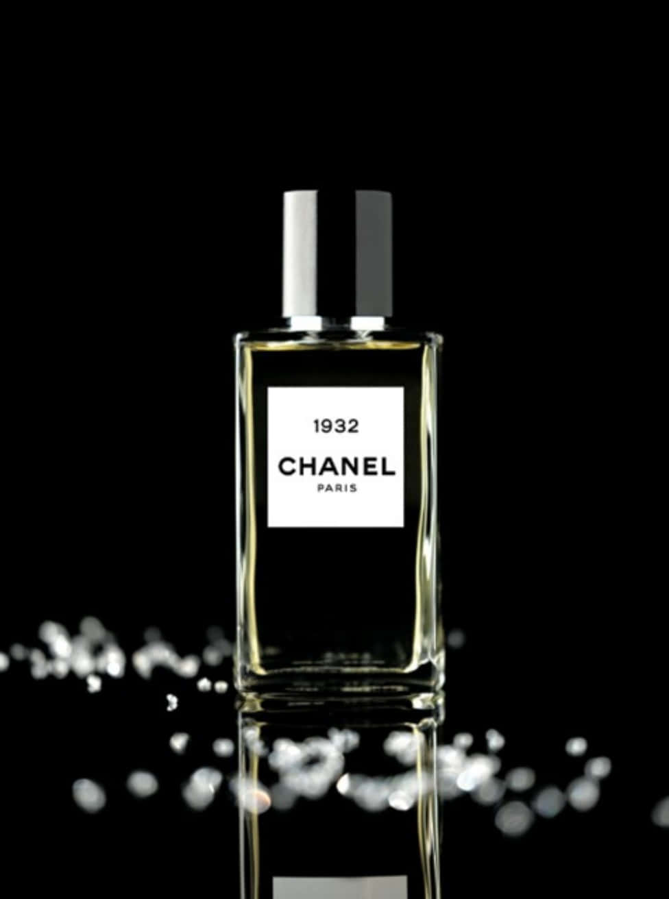 Chanel 桌布 壁紙 — 時尚的 Chanel 1932 香水瓶在黑色背景上閃耀，帶有閃爍的水滴和完美的倒影。