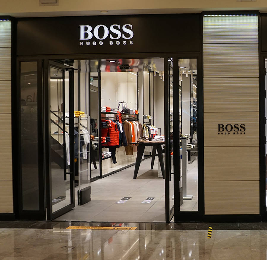 Building 桌布 壁紙 — 時尚的 Hugo Boss 商店入口，配有玻璃門和現代室內照明，展示服裝架。