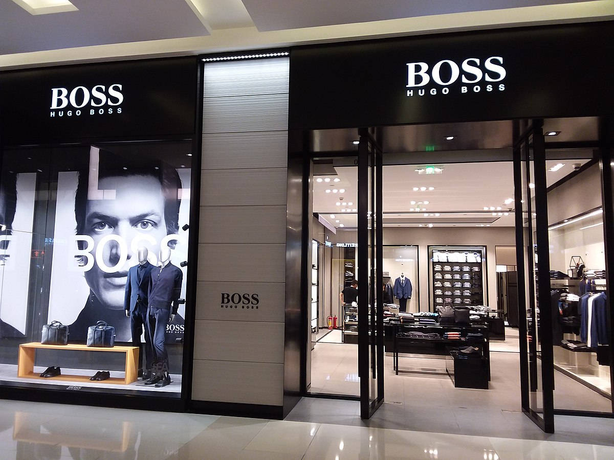 Clothes 桌布 壁紙 — 時尚的Hugo Boss店鋪入口，設有玻璃門和一個大型黑白廣告，廣告中有一位身穿西裝的男士。