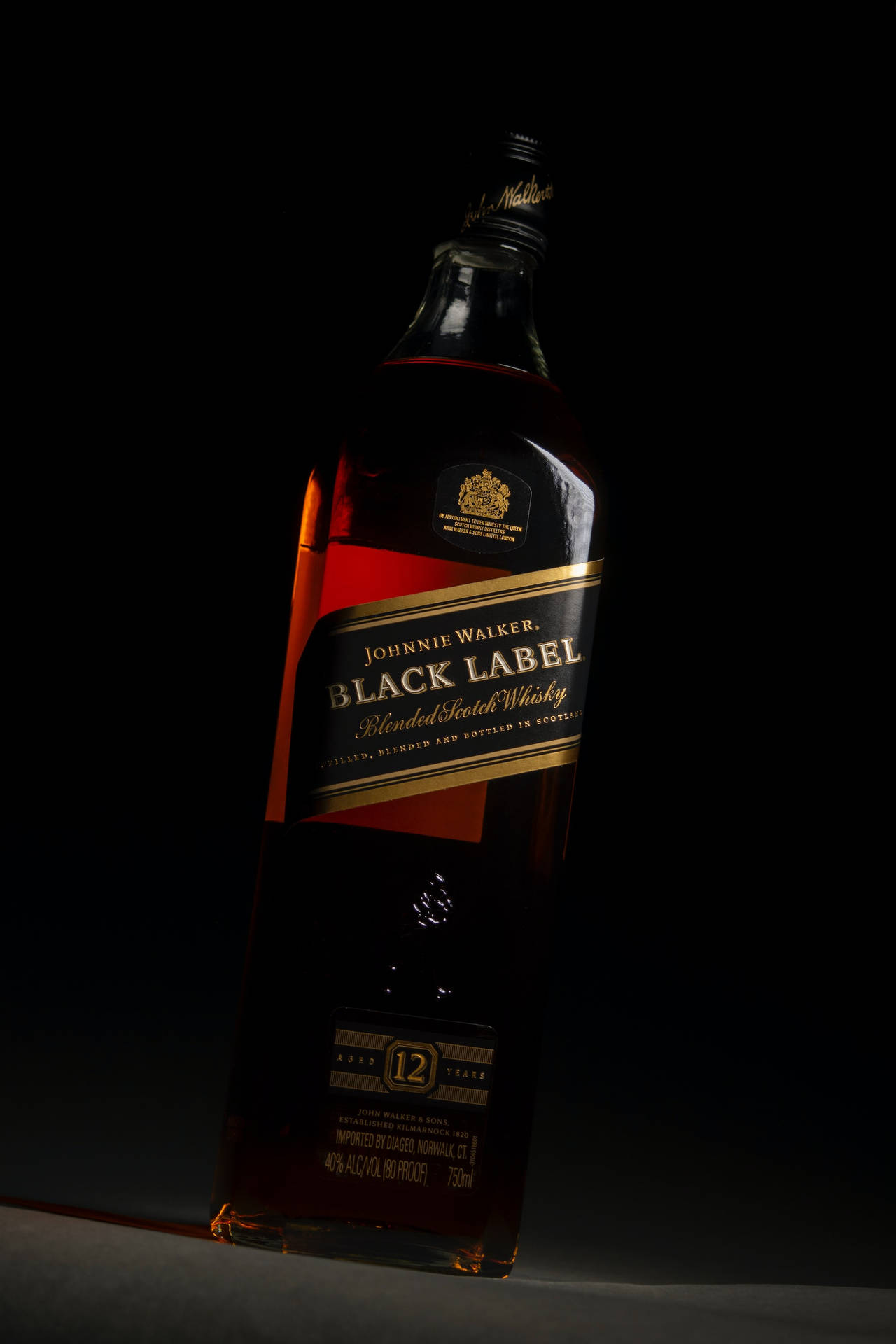 bottle 桌布 壁紙 — 時尚的Johnnie Walker Black Label威士忌酒瓶在純黑背景下閃耀著琥珀色液體。