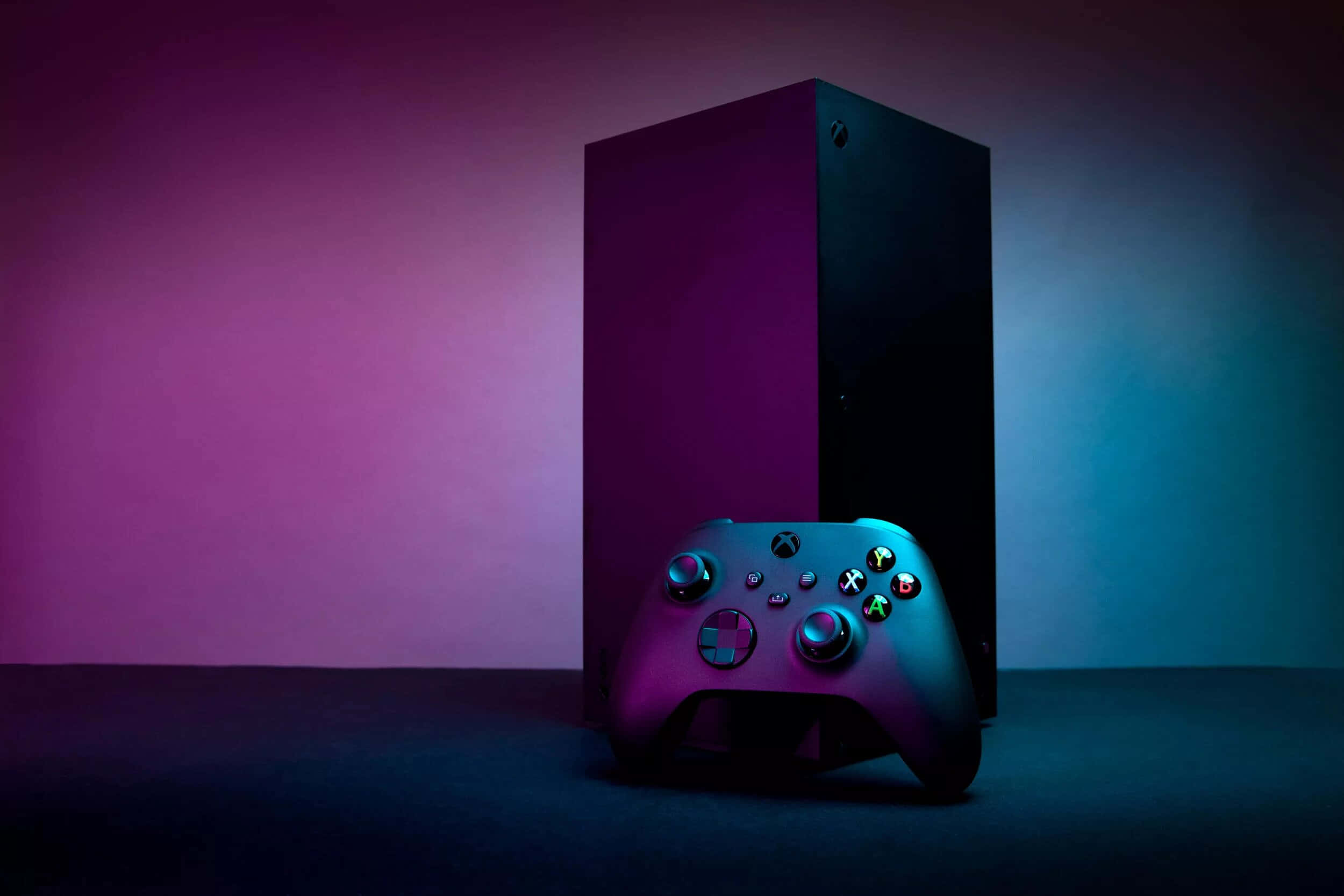 Xbox 桌布 壁紙 — 時尚的Xbox主機和控制器在漸變背景前，在充滿活力的紫色和藍色工作室燈光下閃耀。