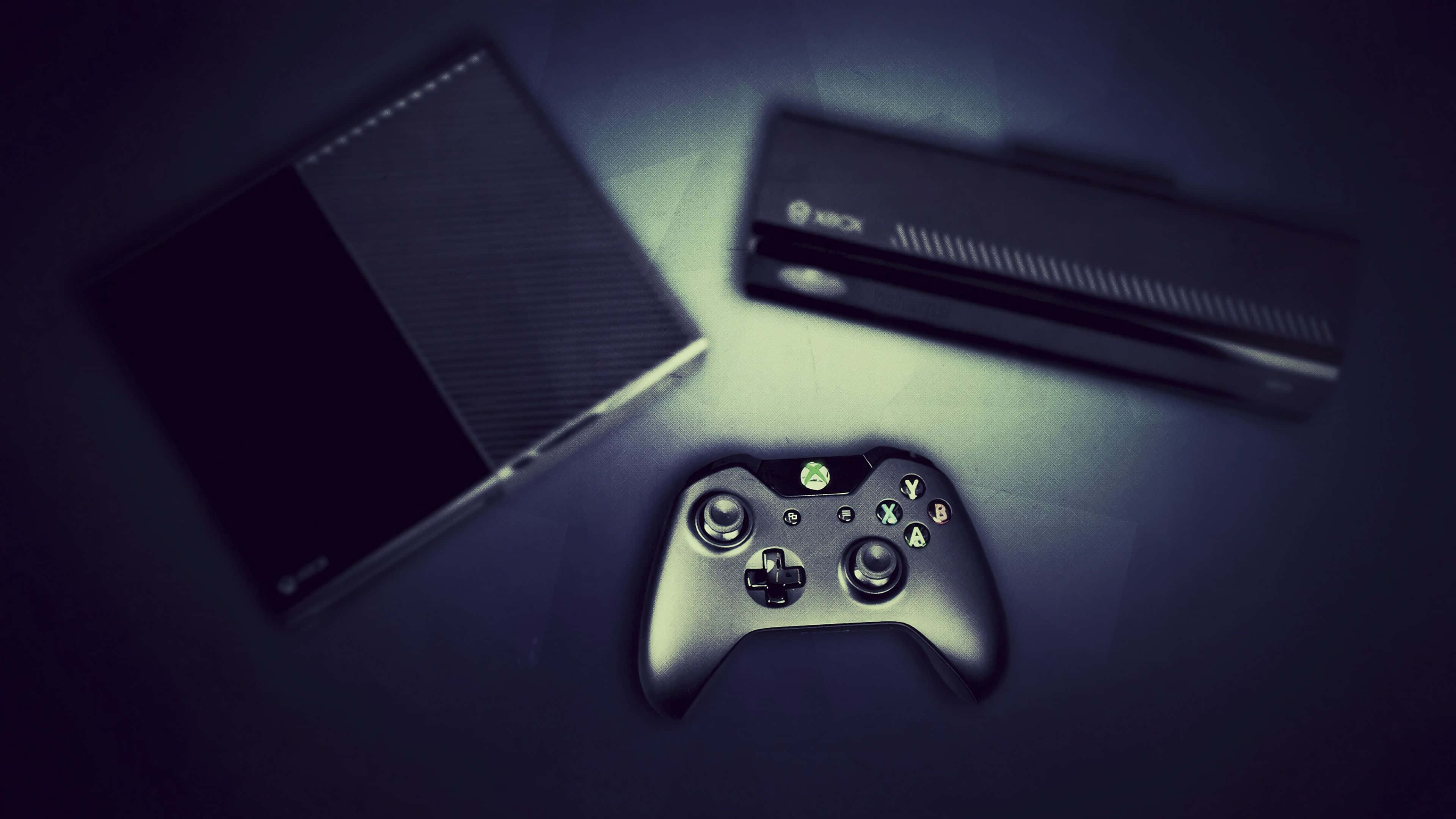 4K Gaming Consoles 桌布 壁紙 — 時尚的Xbox主機和控制器在黑暗表面上戲劇性的聚光燈下休息，散發著冷綠色調。