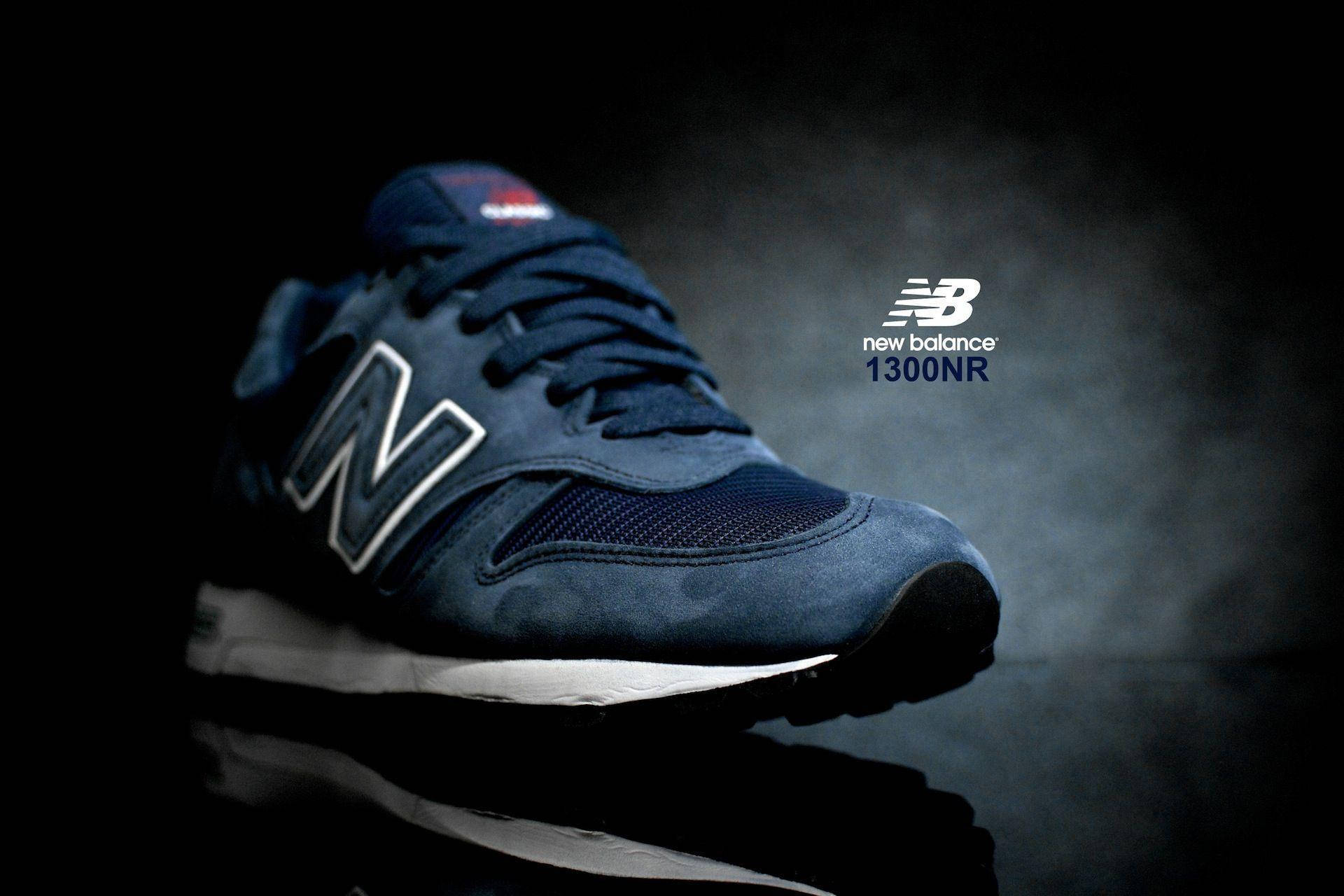 New 桌布 壁紙 — 時尚的深藍色 New Balance 1300NR 運動鞋在戲劇性的聚光燈下，在帶有反射表面的煙霧黑色背景上發光。