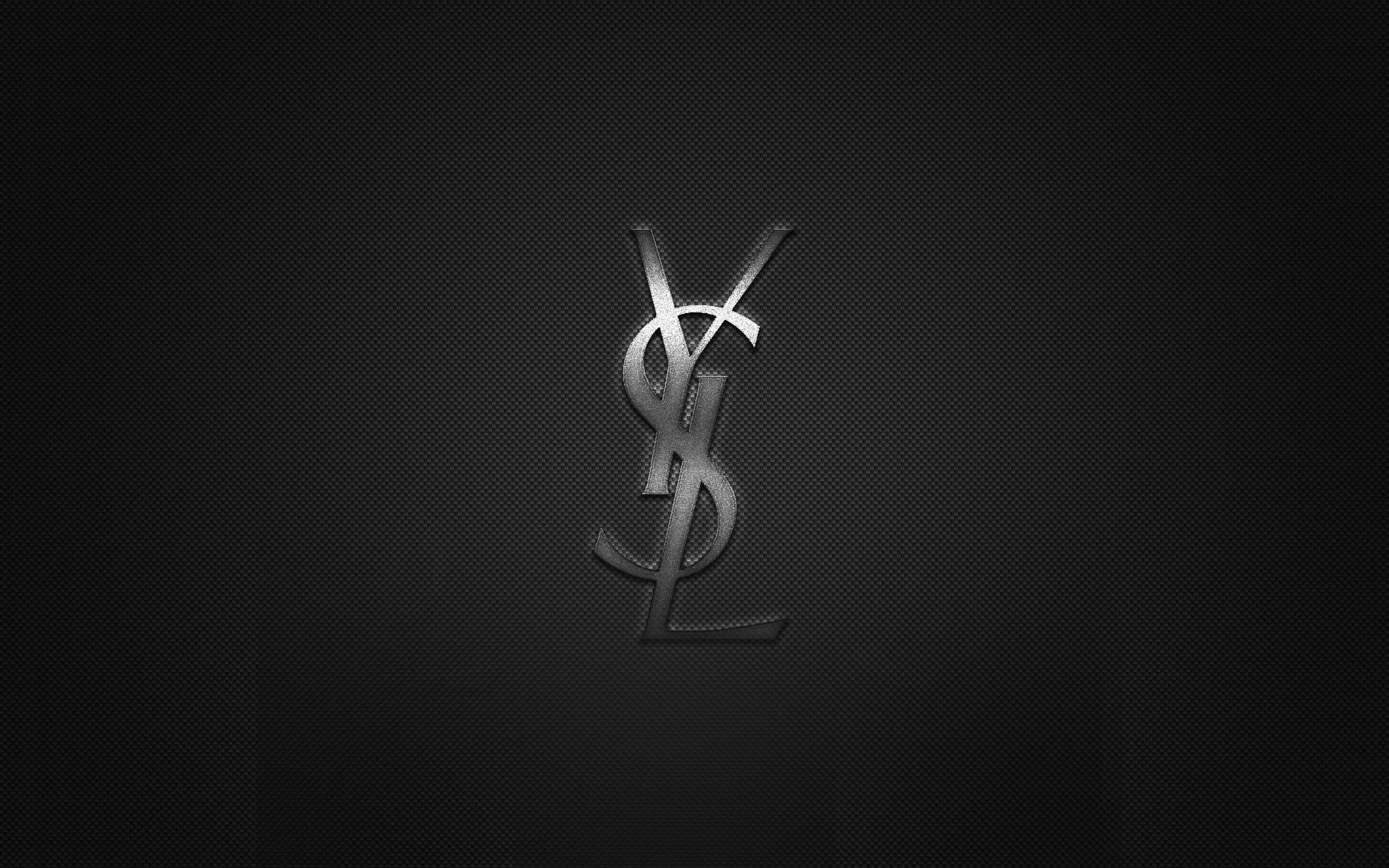 Ysl 桌布 壁紙 — 時尚的銀色YSL標誌在帶有微妙漸變照明的紋理黑色背景上閃耀。