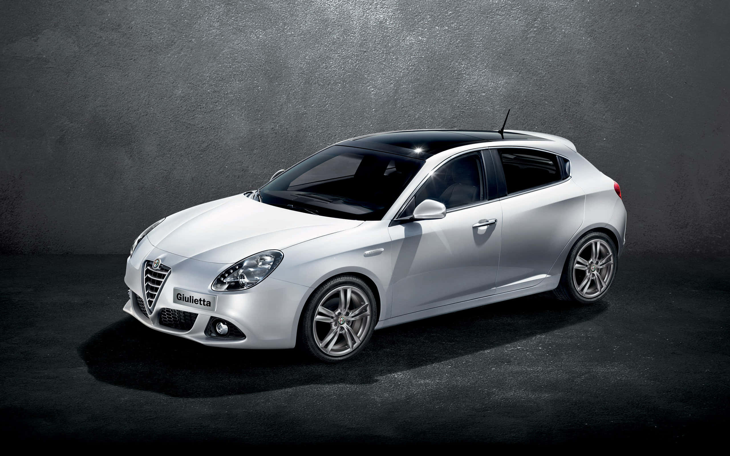 Alfa Romeo Giulietta 桌布 壁紙 — 時尚的銀色愛快羅密歐Giulietta掀背車在深色紋理背景前，於攝影棚燈光下閃閃發光。