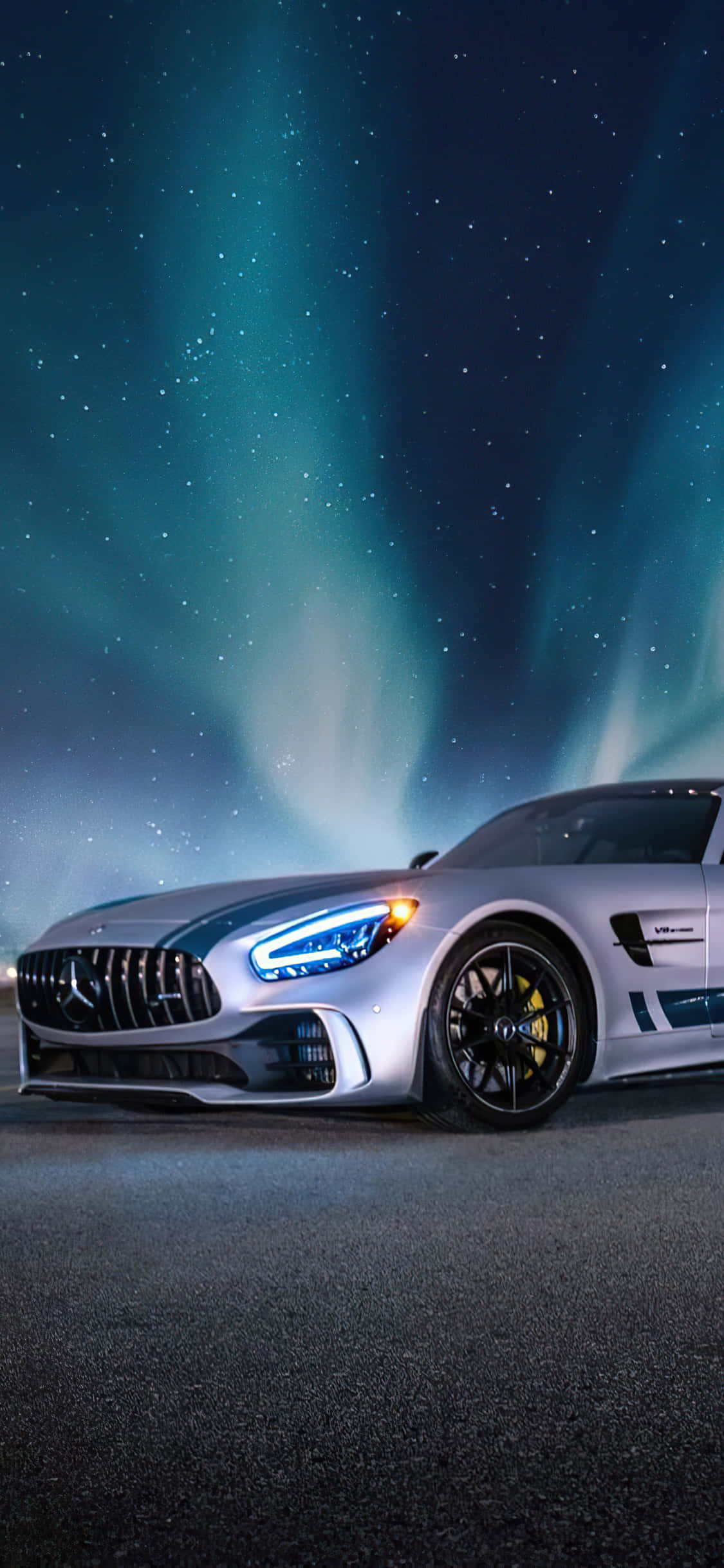 aurora borealis 桌布 壁紙 — 時尚的銀色跑車在充滿活力的綠色極光下閃耀，映襯著星空夜空。