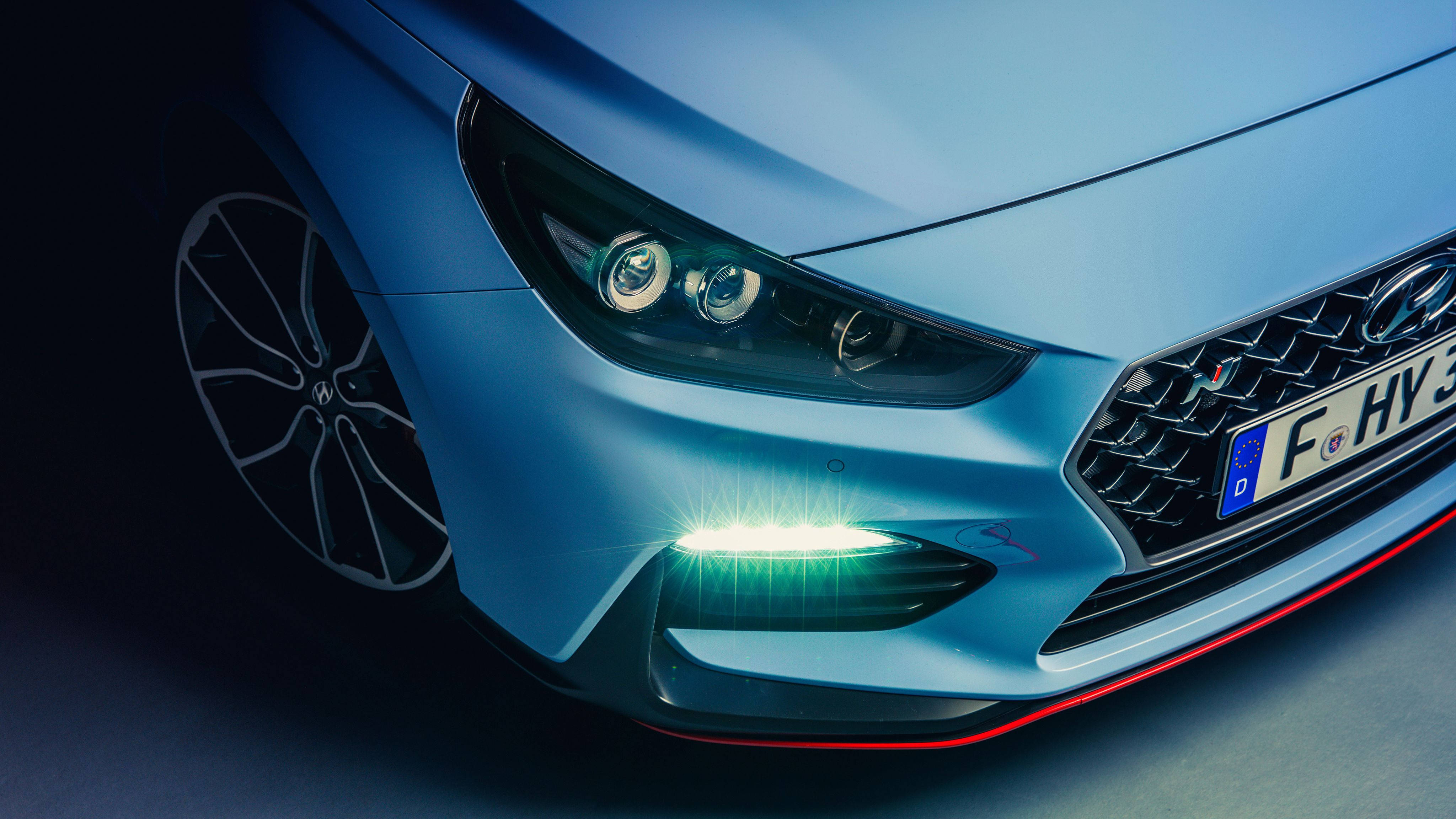 Hyundai 桌布 壁紙 — 時尚藍色跑車前臉的特寫，散發著充滿活力的綠色底盤燈和銳利的LED頭燈。