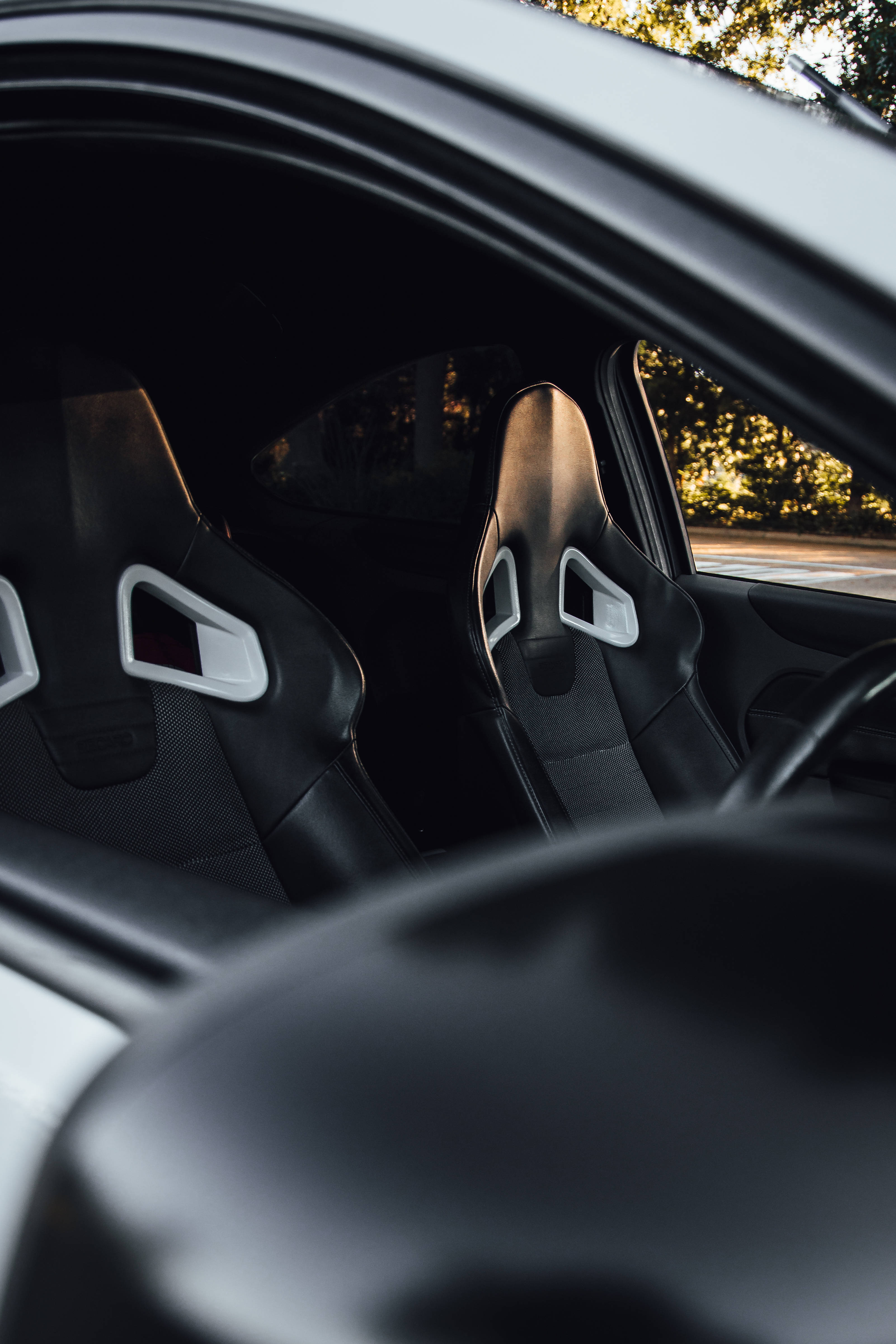 ford iPhone 桌布 壁紙 — 時尚跑車內飾特寫，黑色賽車座椅搭配白色飾邊，沐浴在溫暖的黃金時刻光線中。