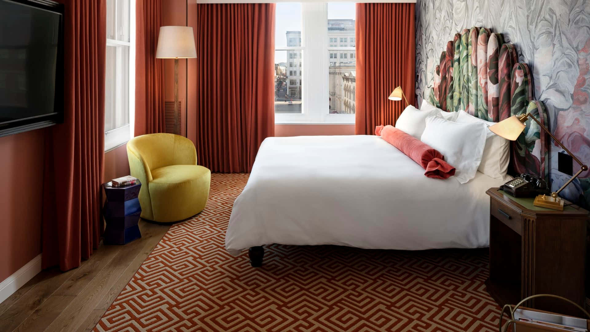 Hotel Room 桌布 壁紙 — 時尚飯店客房，配有白色床、紅色窗簾、黃色扶手椅和圖案地毯，沐浴在自然光中。