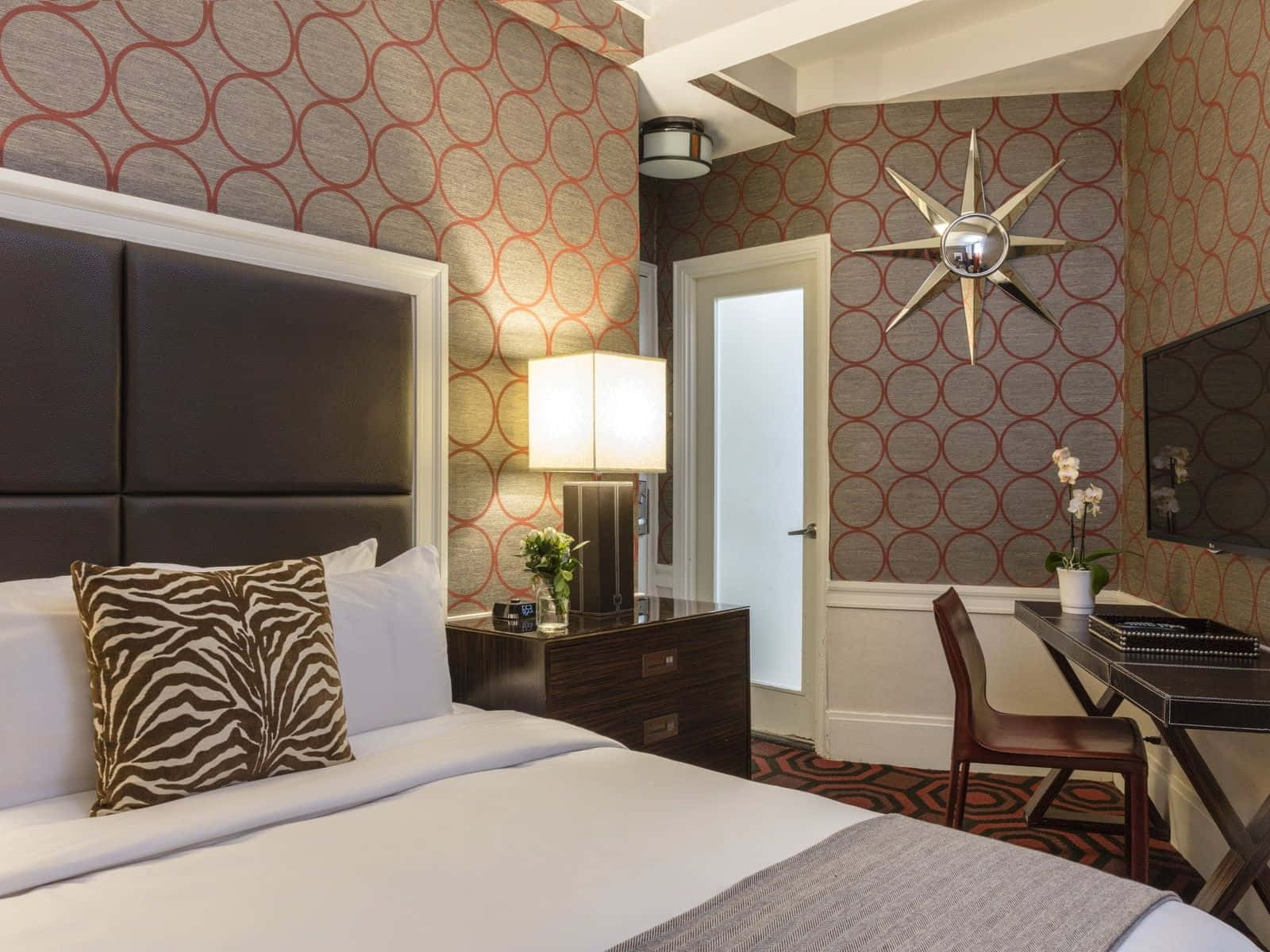 Bedroom 桌布 壁紙 — 時尚飯店房間，配有圖案壁紙、斑馬紋枕頭和書桌上方星爆鏡。